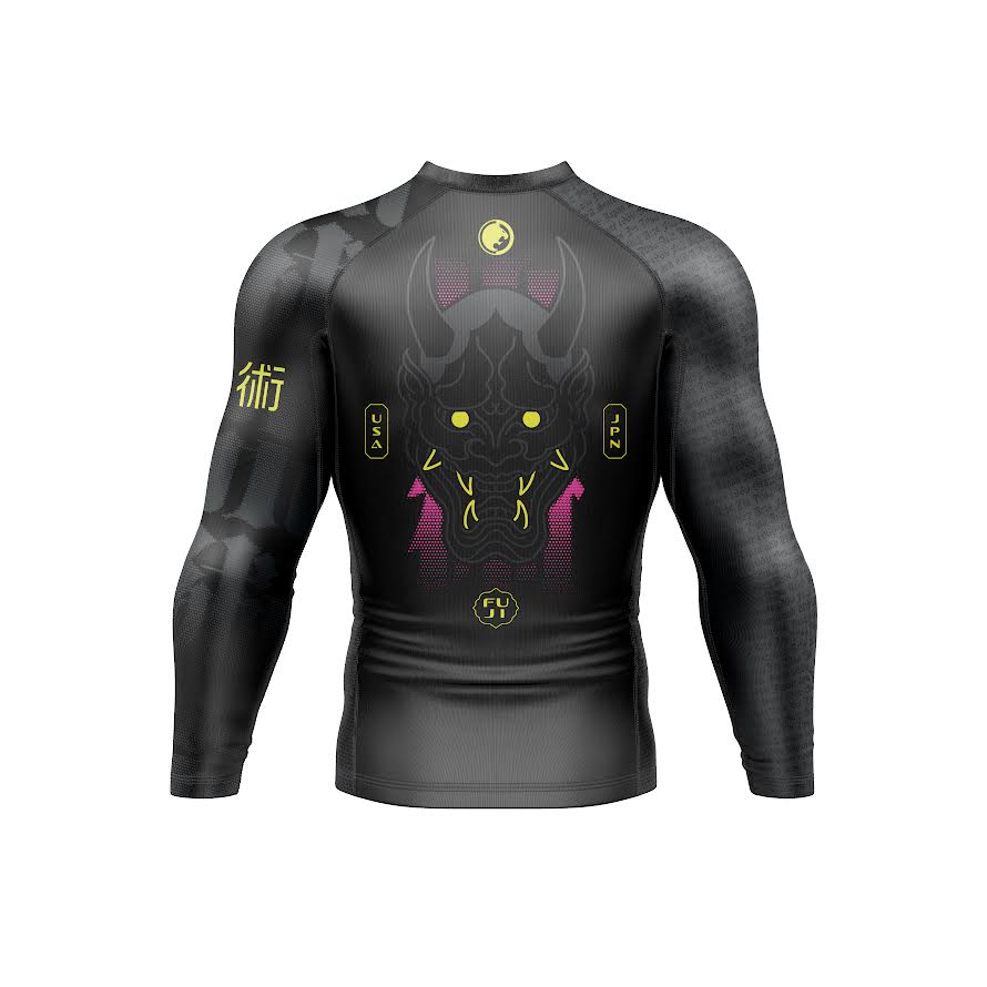 The Renzo Gracie Long Sleeve Rashguard Oni Legend Edition features a black and gray design with a neon-accented demon face, yellow symbols, and geometric patterns on the back, displayed on a plain white background.