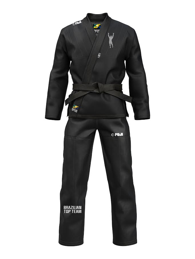 The BTT 25th Anniversary Ultra Lite Black gi comes with a black belt, features FUJI and BRAZILIAN TOP TEAM logos, a small Brazilian flag patch, and a silhouette figure on the left chest.