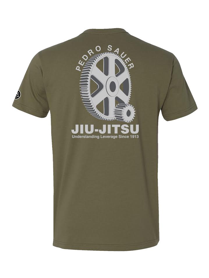 The Pedro Sauer Leverage T-Shirt in military green features a large white gear graphic and "Pedro Sauer Jiu-Jitsu, Understanding Leverage Since 1913" on the back, with a small circular logo on the left sleeve.