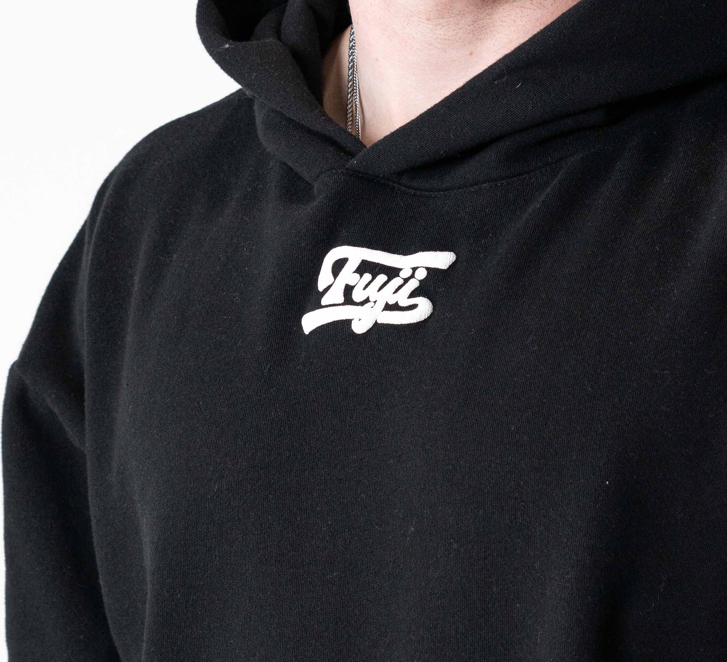A person models the Signature Hoodie Black, featuring “Fuyi” in white script on the chest. Only the lower face and upper torso are visible.