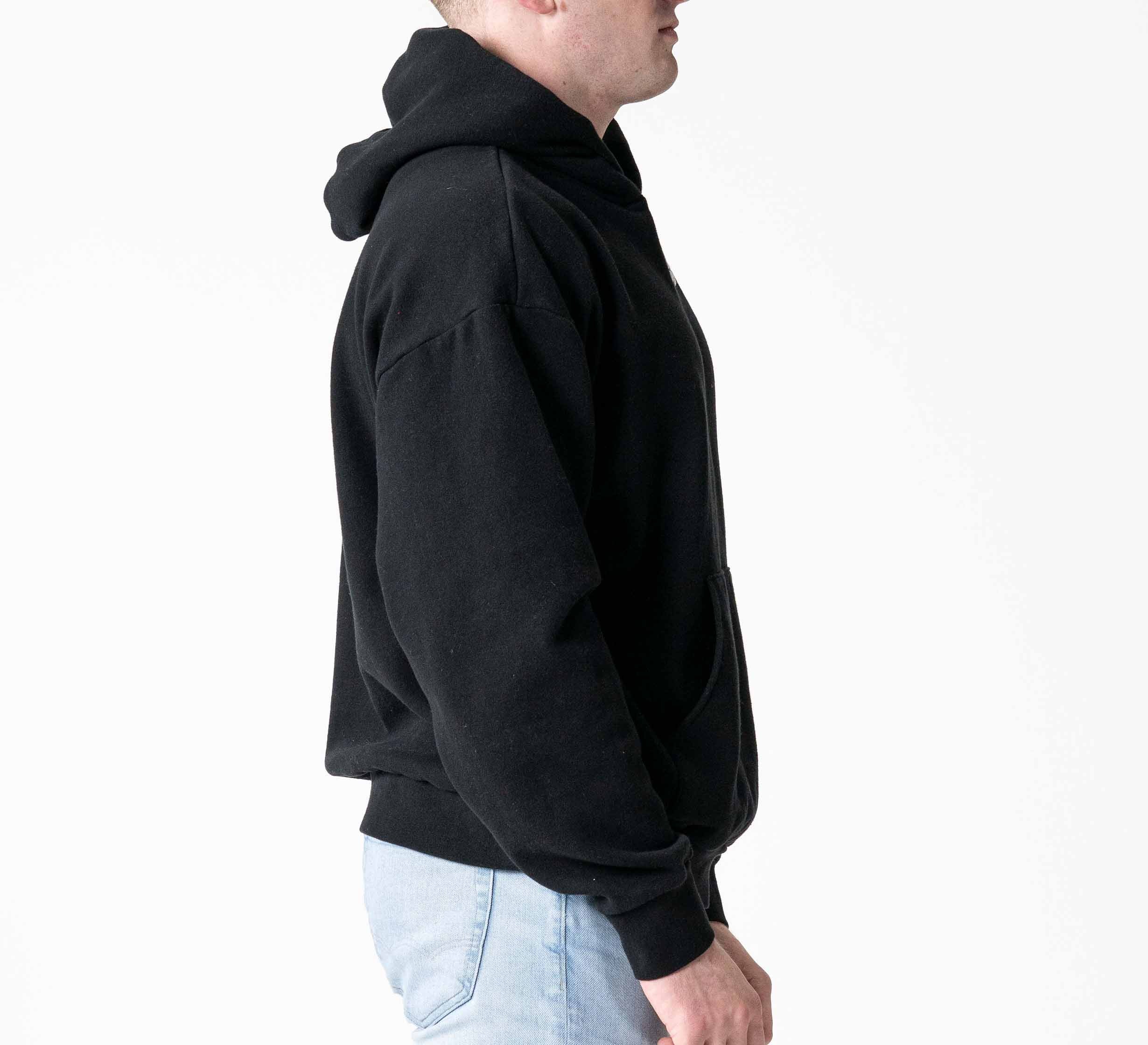 A person in the Signature Hoodie Black and light blue jeans stands in profile against a plain white background.