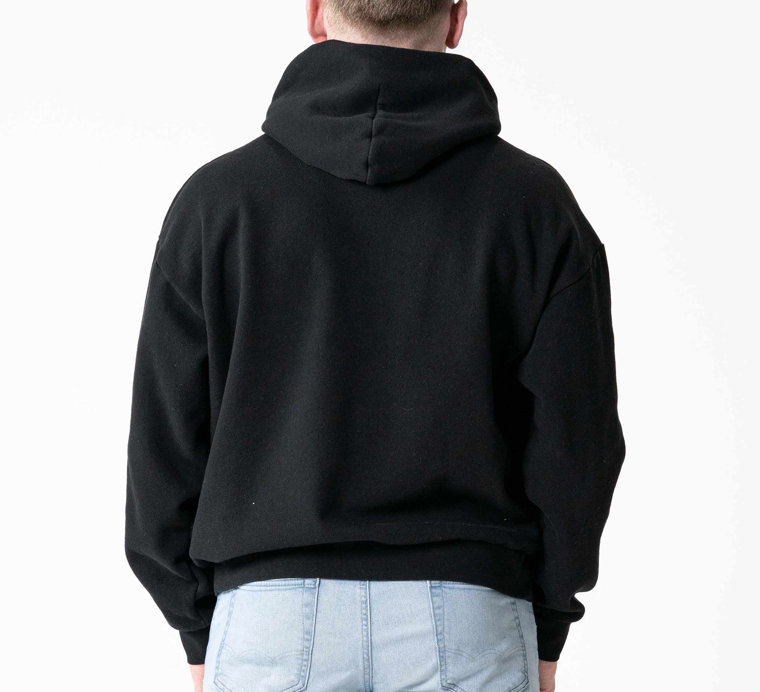 A person is seen from the back wearing the Signature Hoodie Black and light blue jeans, set against a plain white background.