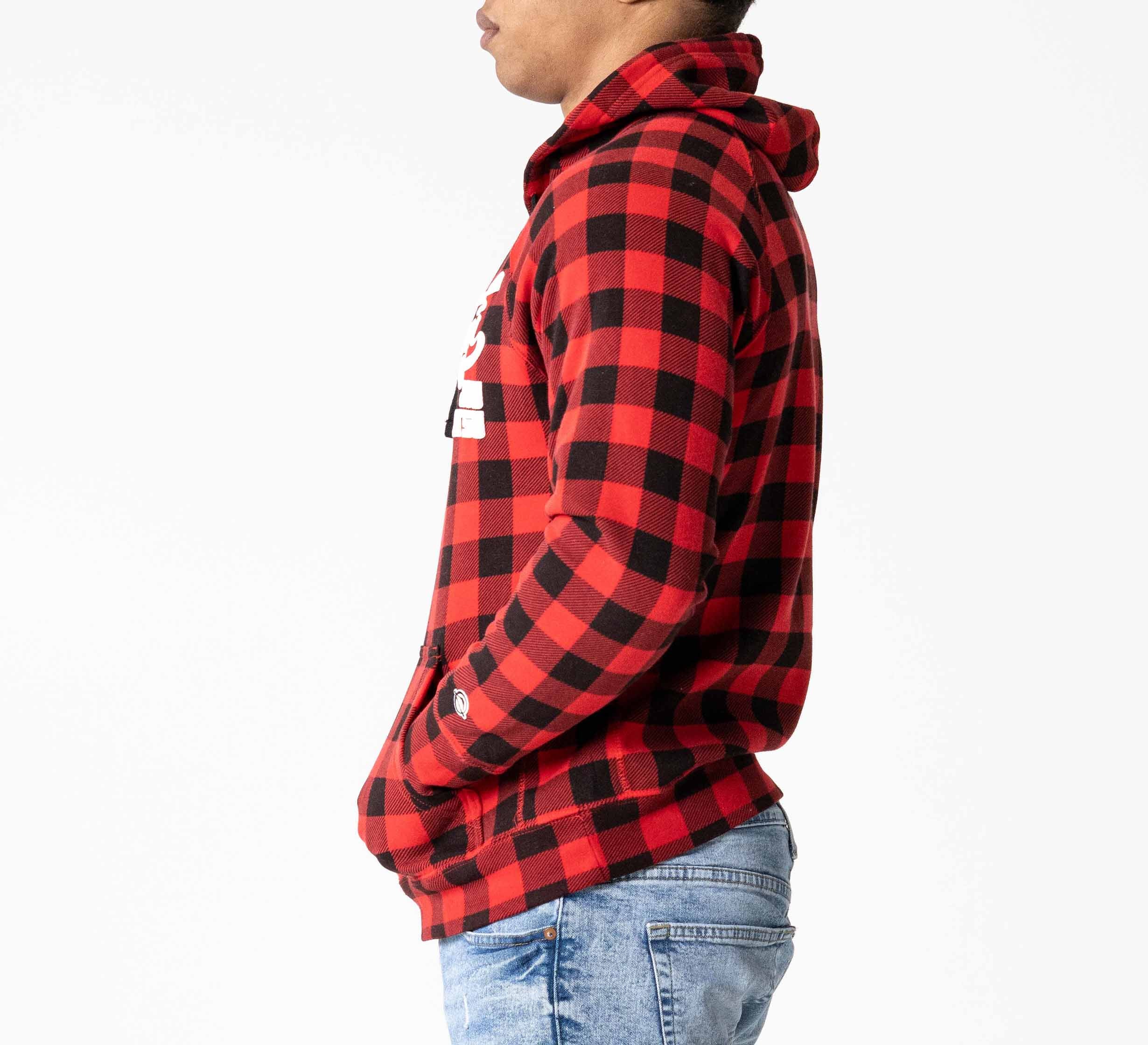 Wearing the Signature Hoodie Red Plaid with hands in pockets, a person stands in profile facing left, paired with light blue jeans, all set against a plain white background.