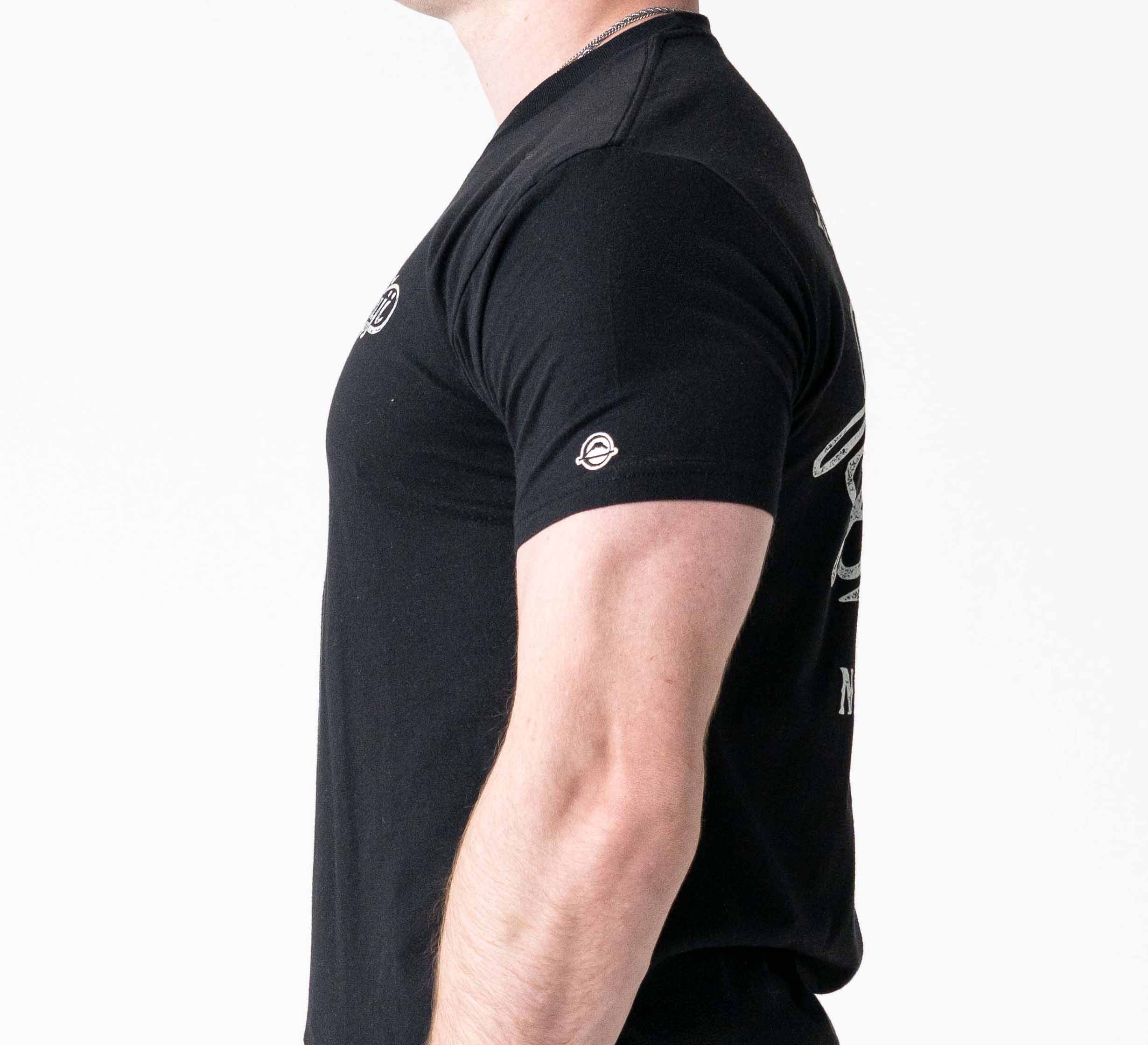 A person wearing the Jiu Jitsu Flow T-Shirt Black, featuring a fitted design with small white logos on the sleeve and chest, is shown from the side against a plain white background.