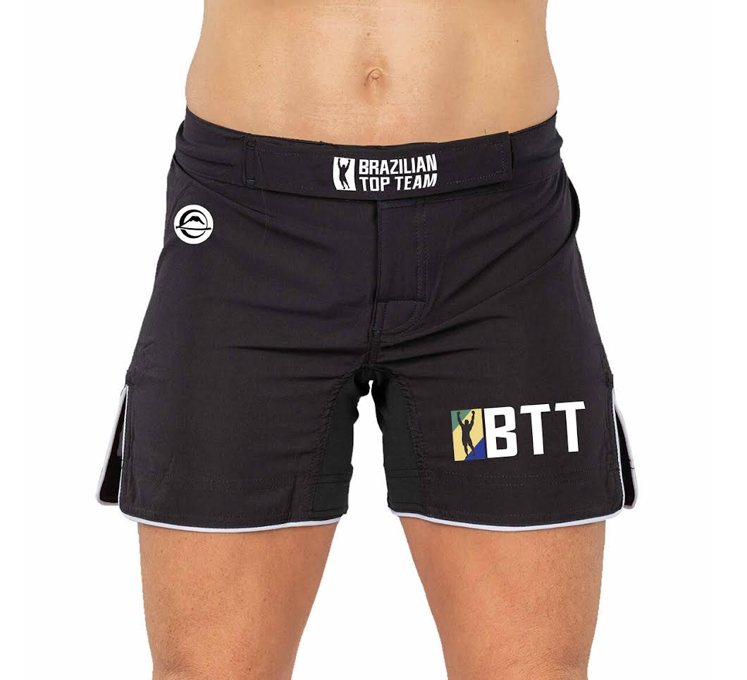 A person wearing BTT Womens Baseline Shorts Black, featuring the Brazilian Top Team branding and a BTT logo on the left leg, shown from waist to mid-thigh.