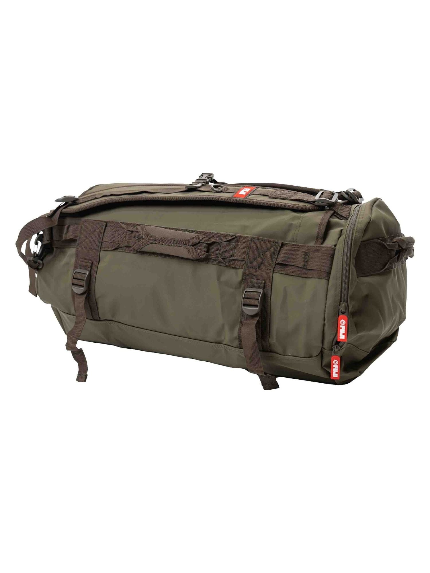 The Comp Convertible Backpack Duffle Military Green features black straps and handles, multiple buckles, and red zipper tags, shown against a white background.