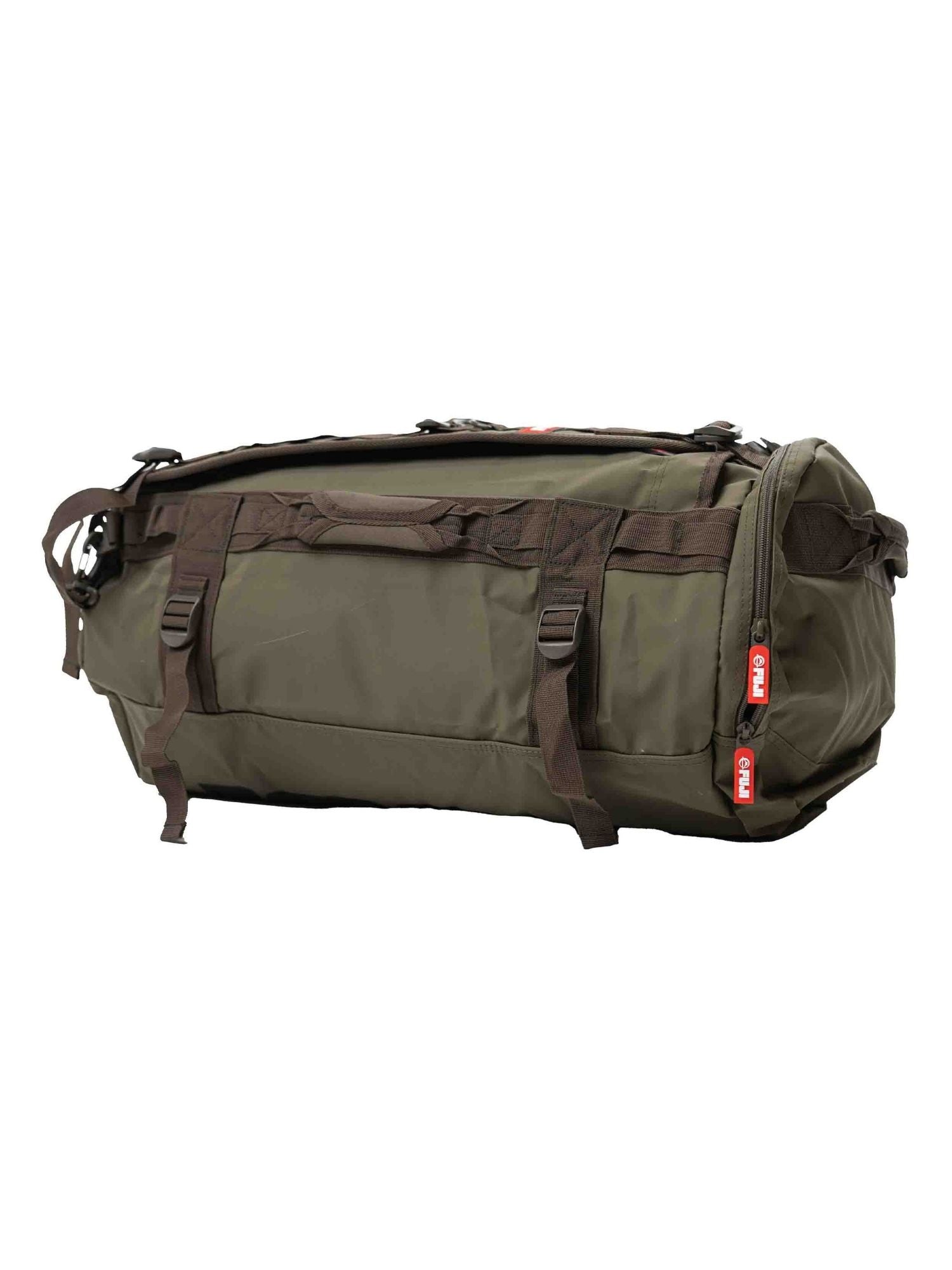 The Comp Convertible Backpack Duffle in Military Green features multiple brown straps, handles, and red zipper pulls. Displayed on a white background.