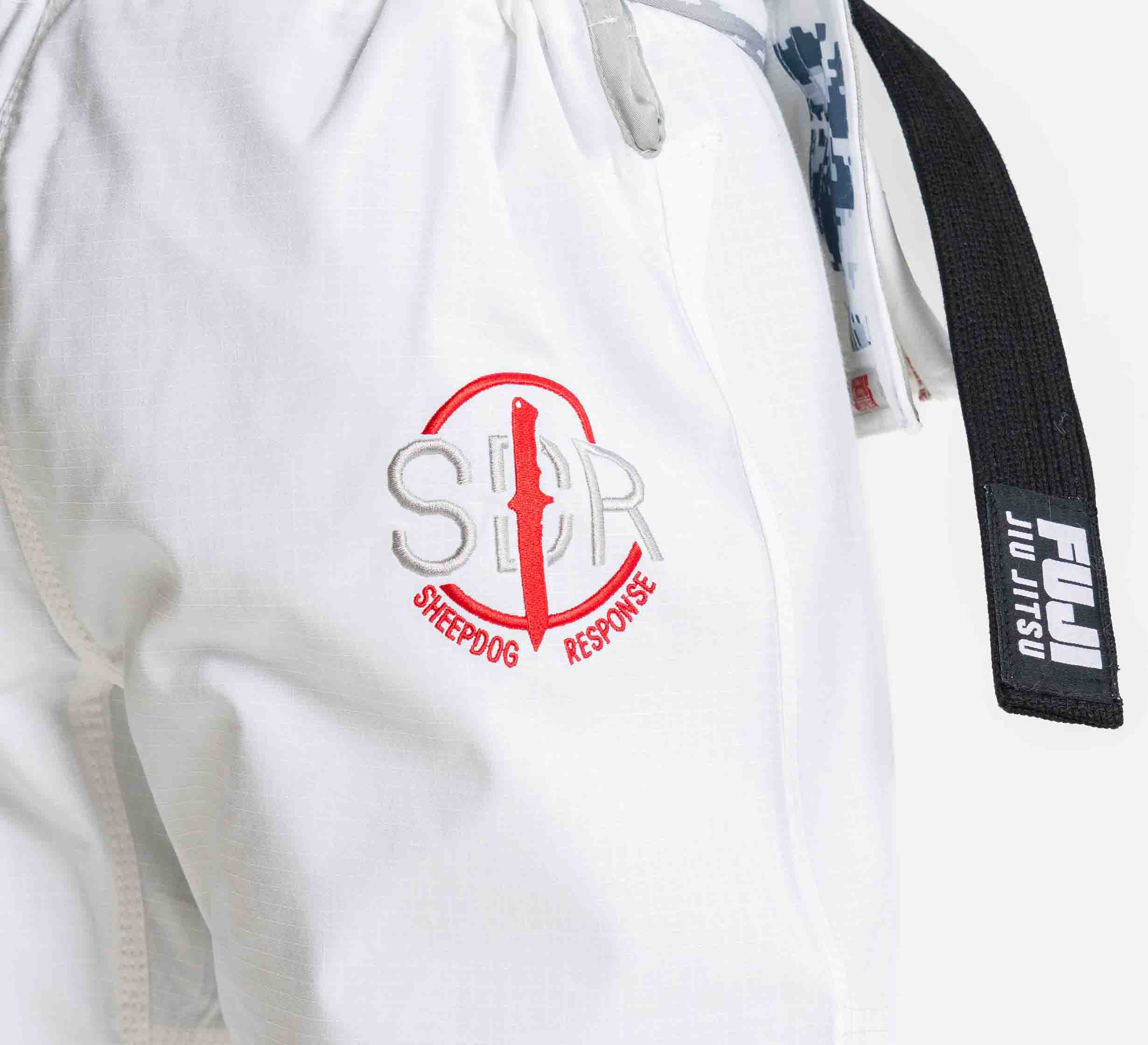Close-up of the Suparaito BJJ Gi Sheepdog Response Edition White, featuring the logo and a red knife graphic, with a black FUJI Jiu Jitsu belt draped on the side.