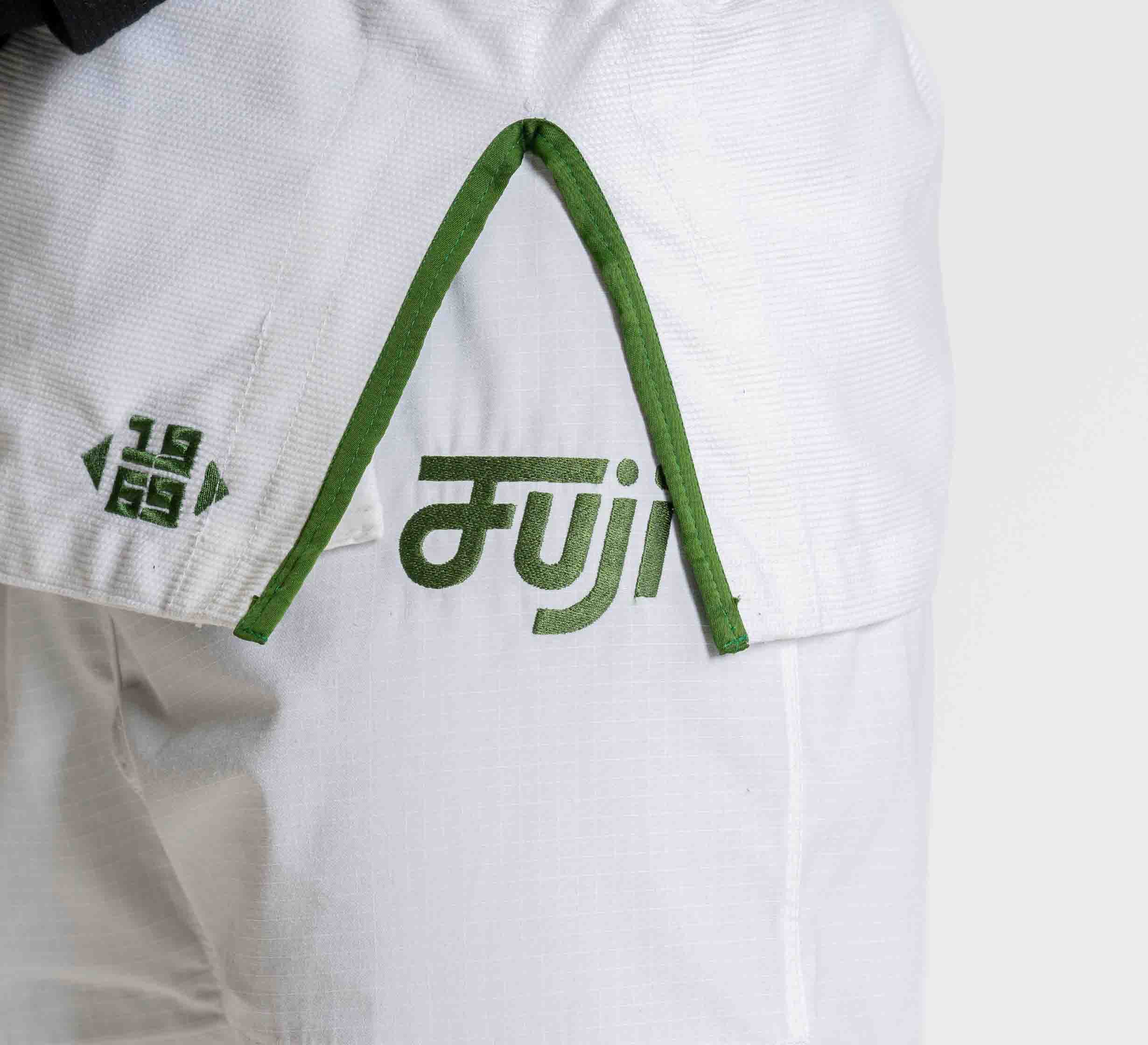 Close-up of the Flow-Tech BJJ Gi in white with green trim, featuring the Fuji logo and "1969" printed in green on the fabric.