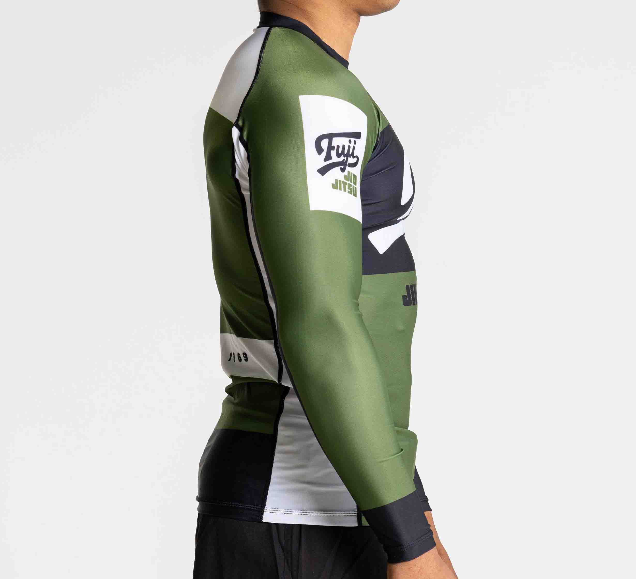 A person models the Jiu Jitsu Script Flex Lite Long Sleeve Rashguard in green, black, and white with Fuji Jiu Jitsu branding on the upper arm, shown from a side view against a plain background.