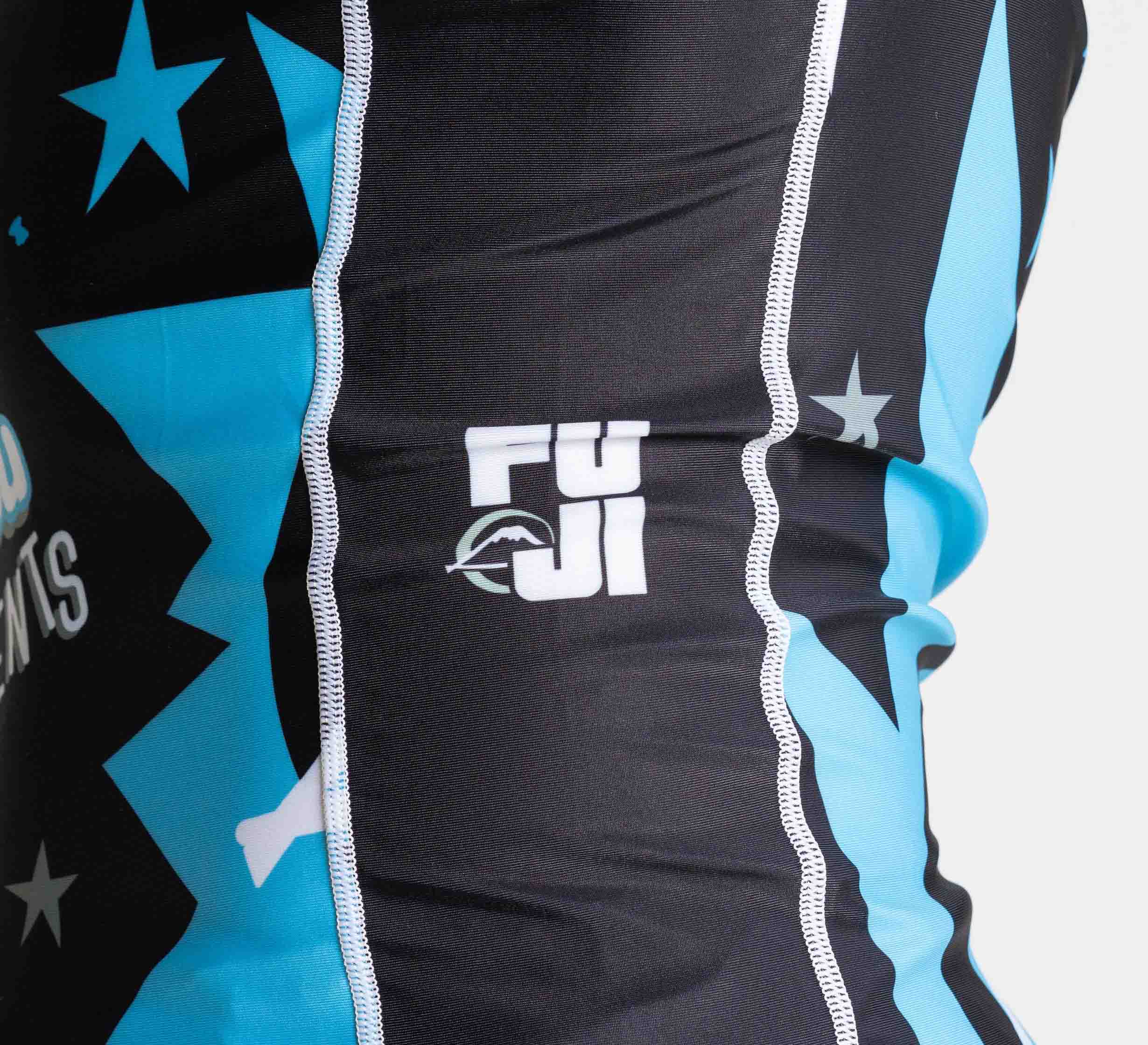 Close-up of the Leg Locks Flex Lite Rashguard Black, showing black and blue athletic fabric with white stars, FUJI text, a mountain logo, and vertical white stitching.