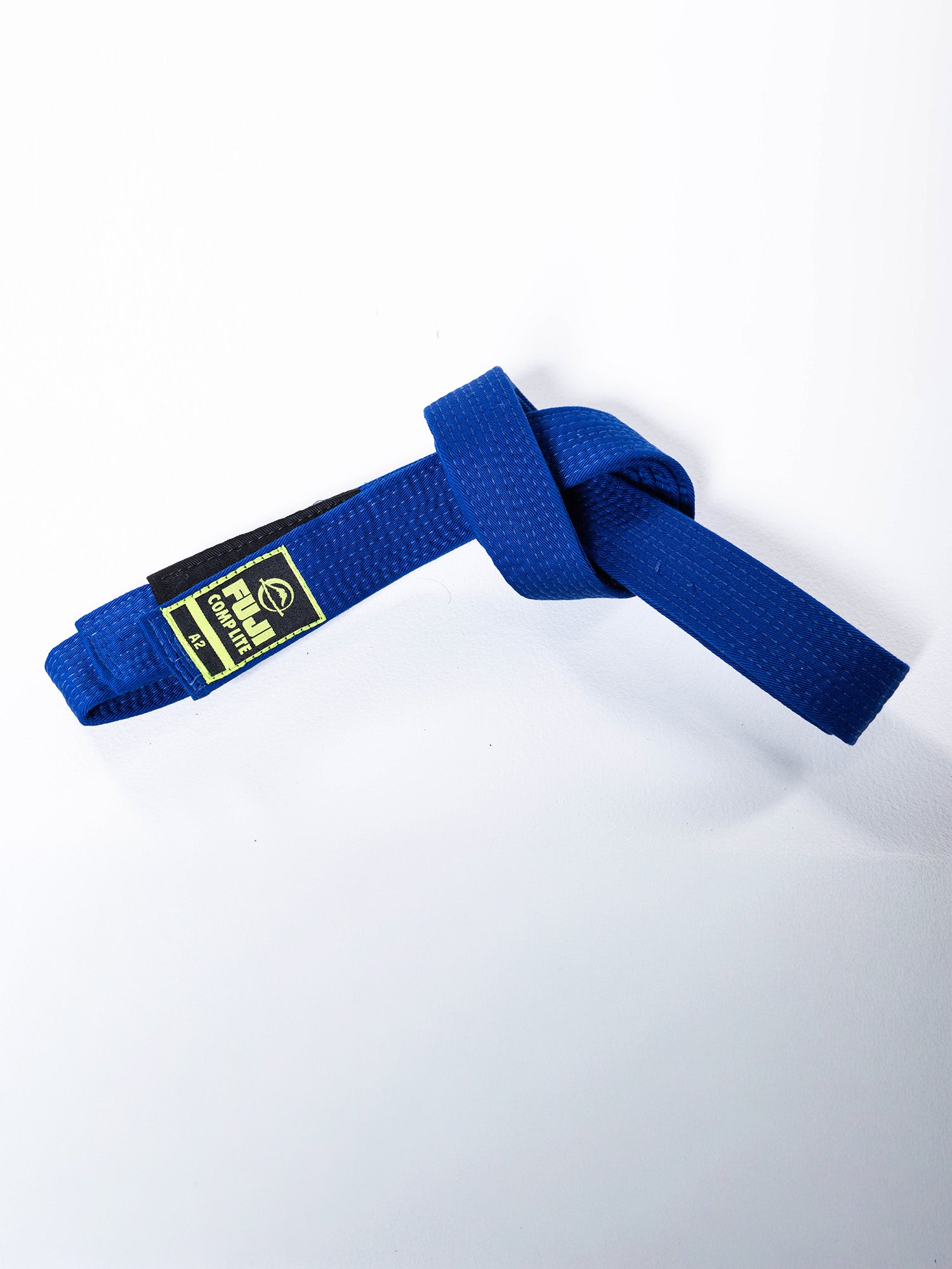 The BJJ Comp Lite Belt Blue, featuring a black and yellow patch, is tied in a knot on a plain white background.