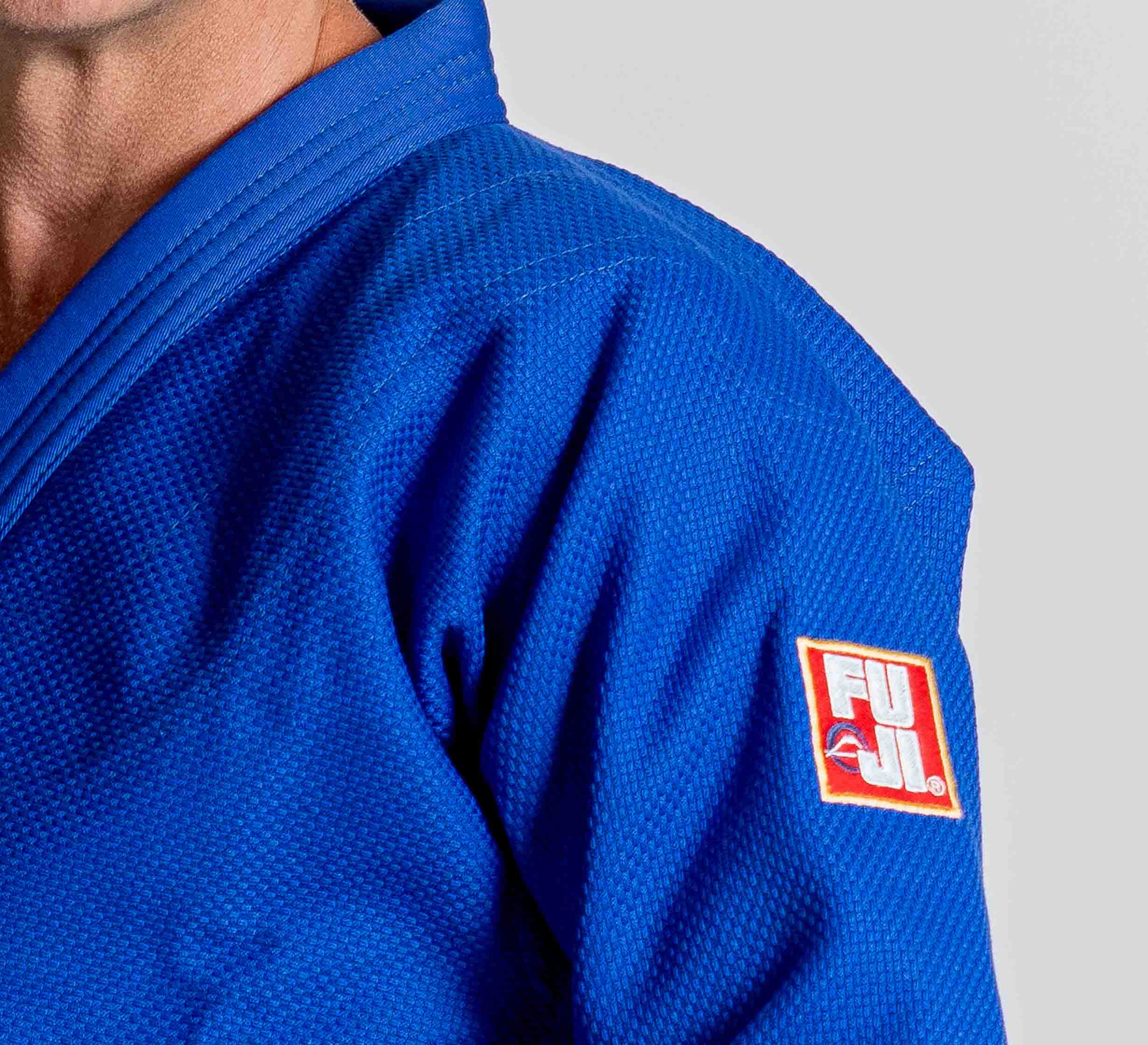 A person wearing the Euro Competition Judo Gi Blue, featuring a FUJI patch on the sleeve; only their upper torso and part of their face are visible.