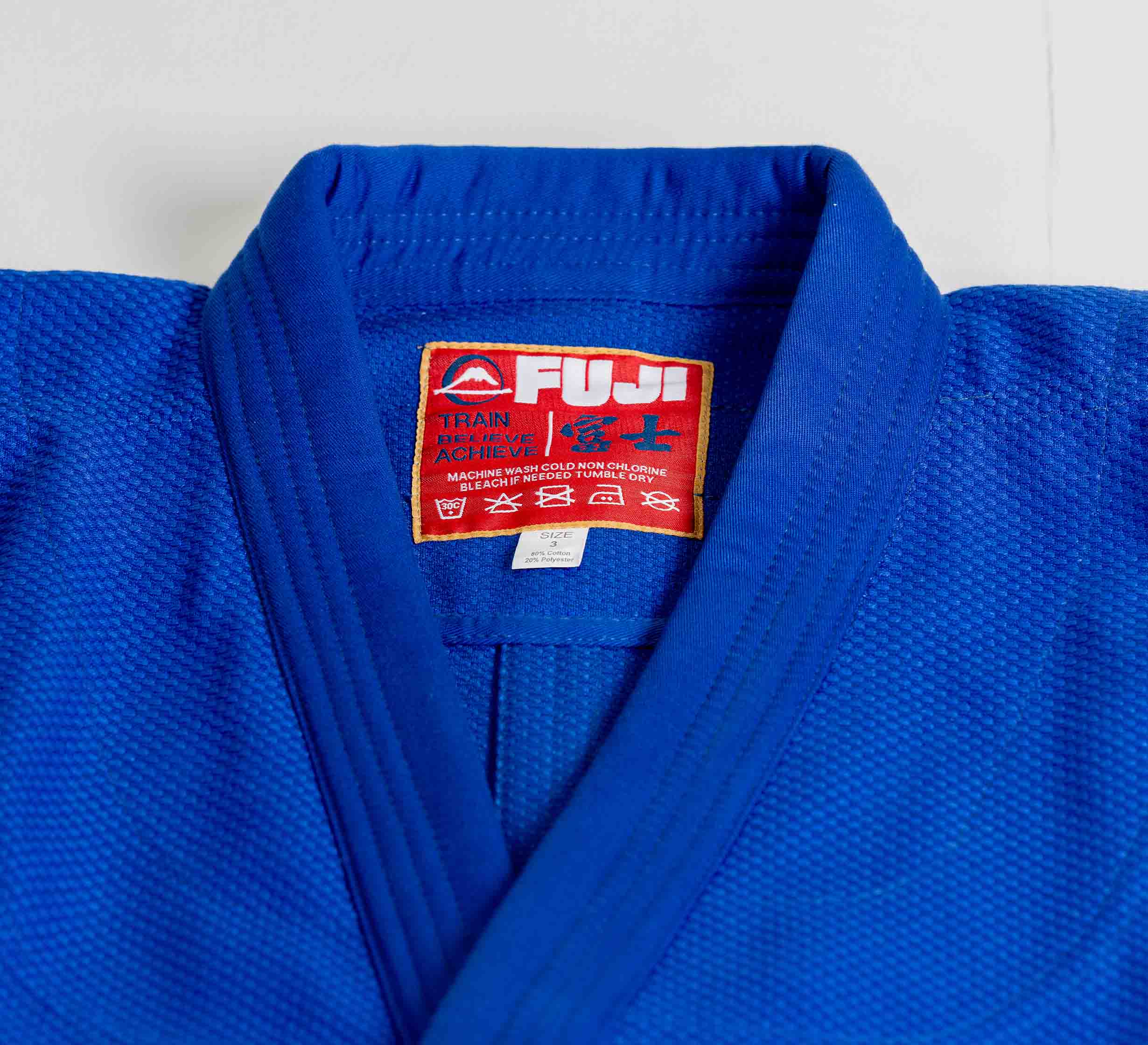 The Euro Competition Judo Gi Blue features a red Fuji brand label with white and red text and care symbols on the inside collar.
