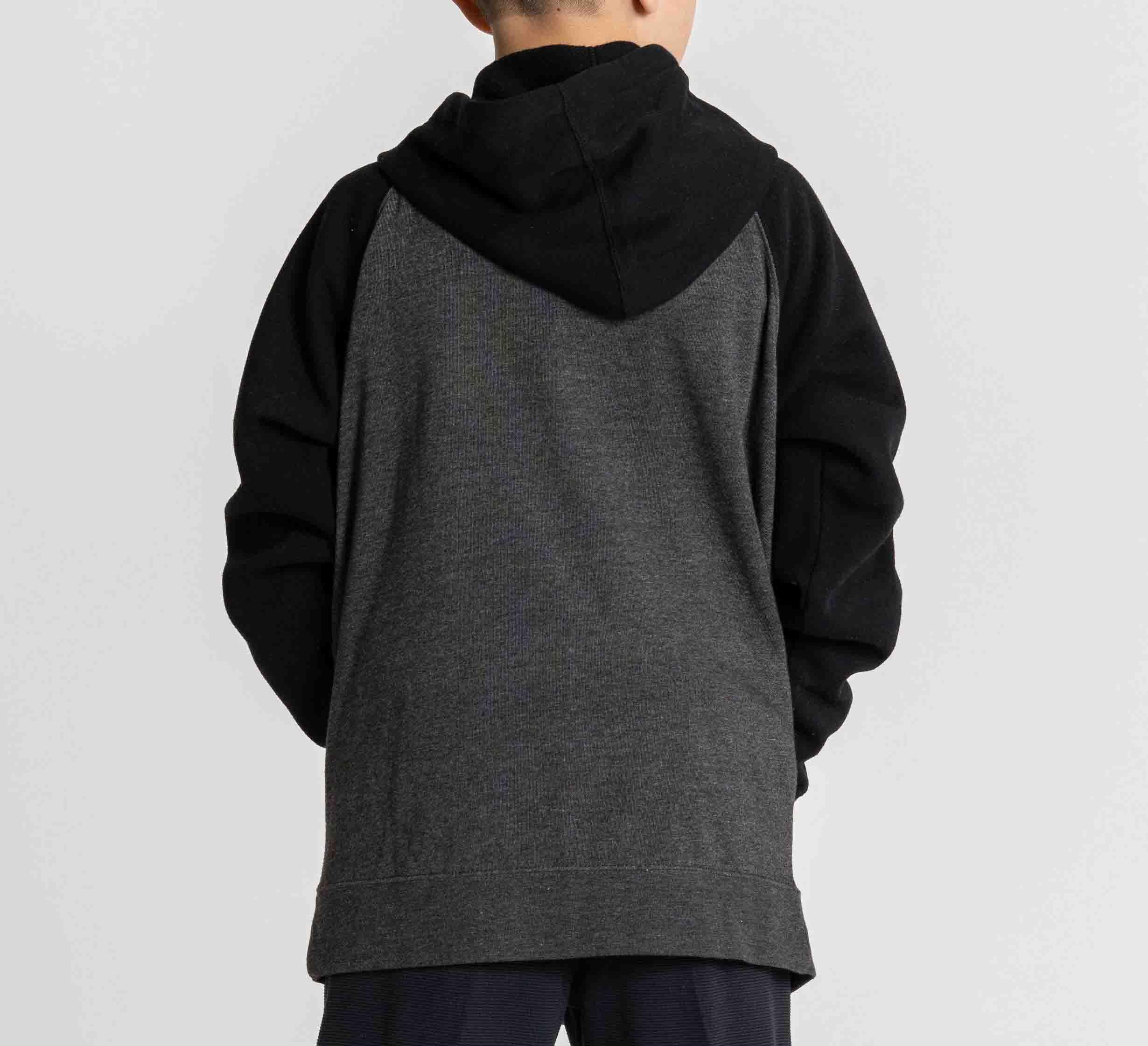 A child wears the Kids Jiu Jitsu Varsity Zip Hoodie in charcoal, facing away from the camera with hands in pockets, set against a plain light background.