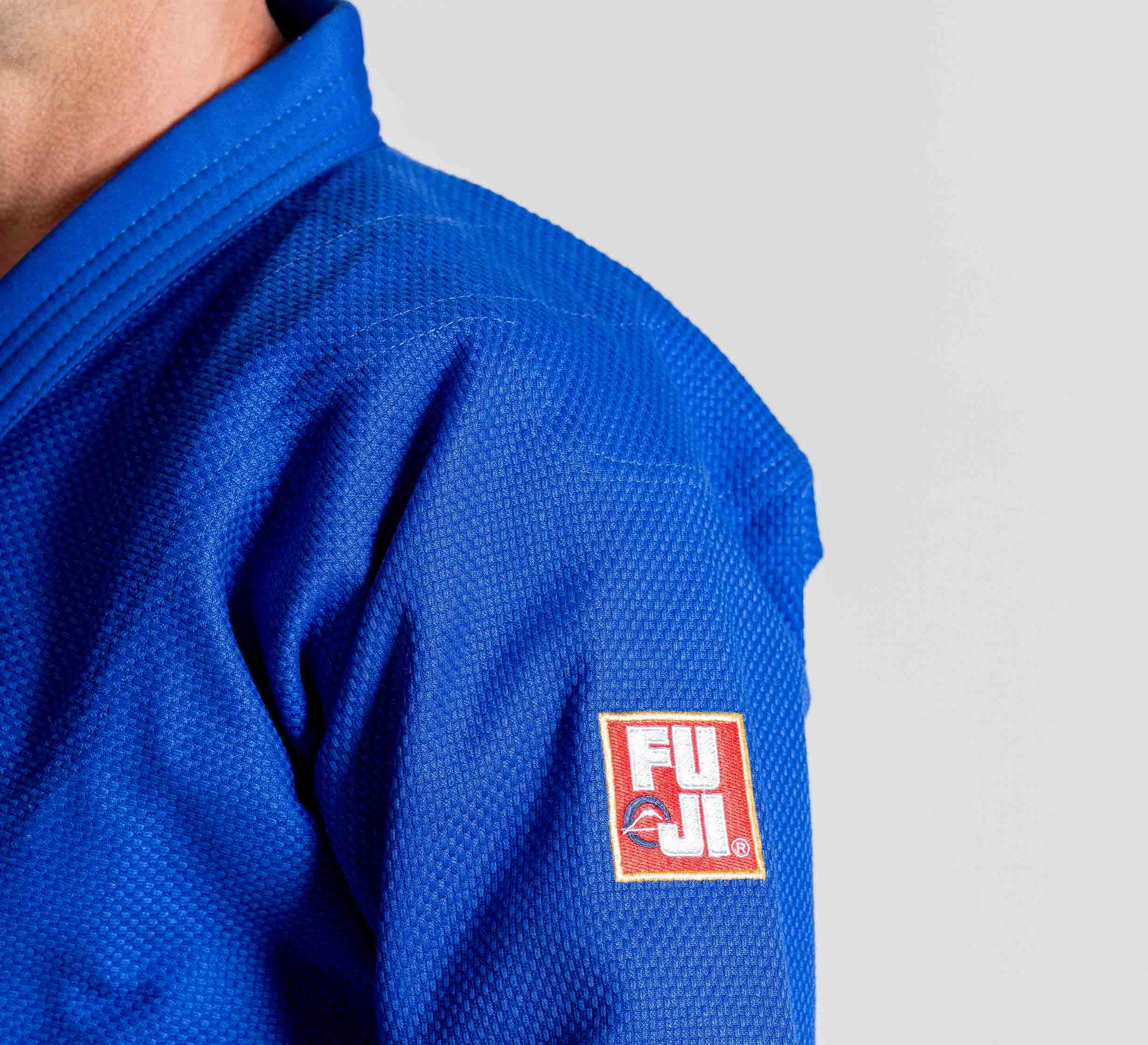 A person wears the Euro Competition Judo Gi Blue with a visible FUJI logo patch on the sleeve, shown from the shoulder down against a plain background.