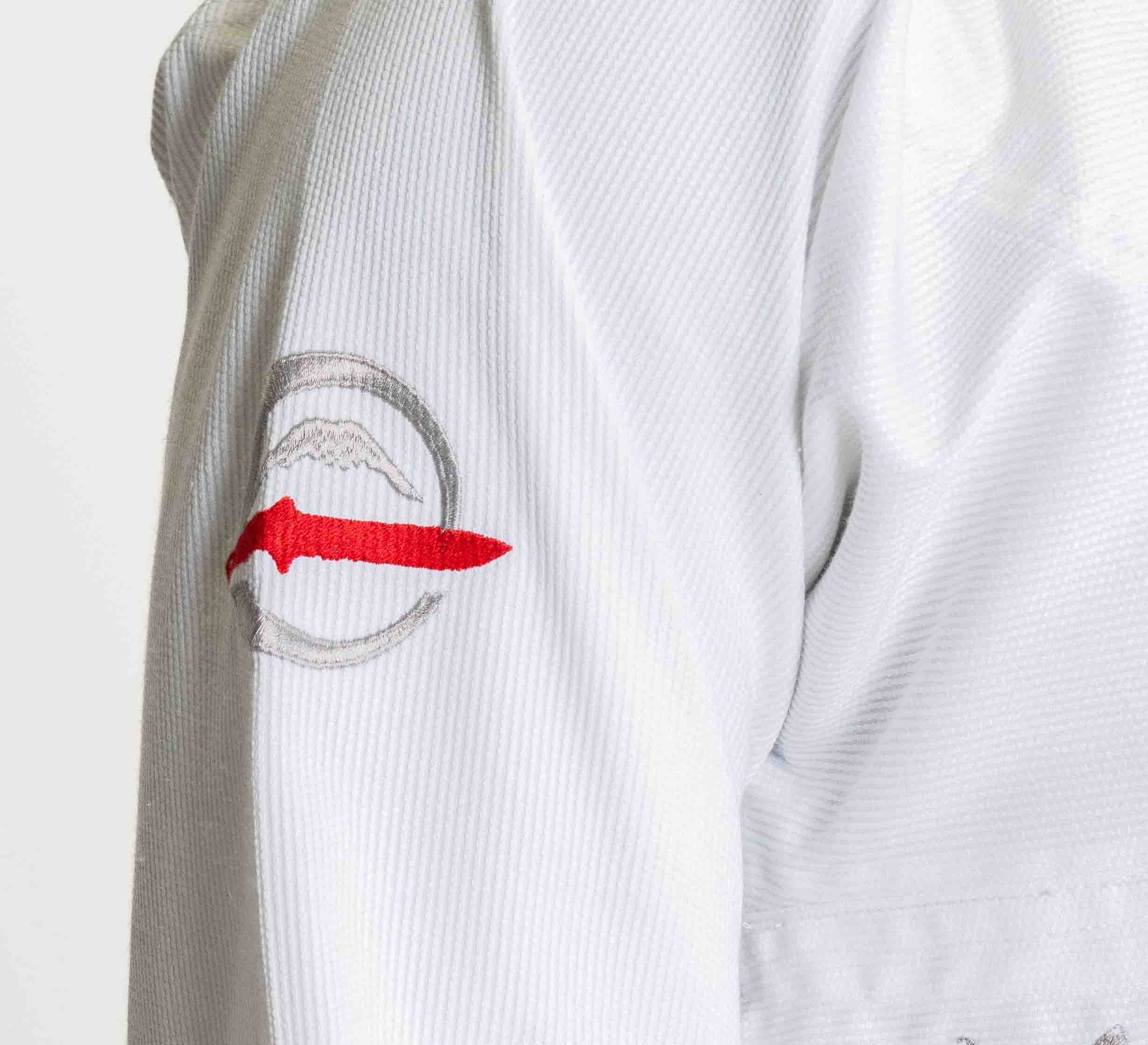 A close-up of the Suparaito BJJ Gi Sheepdog Response Edition White sleeve, showing a circular patch with a gray outline and a red knife design at the center.