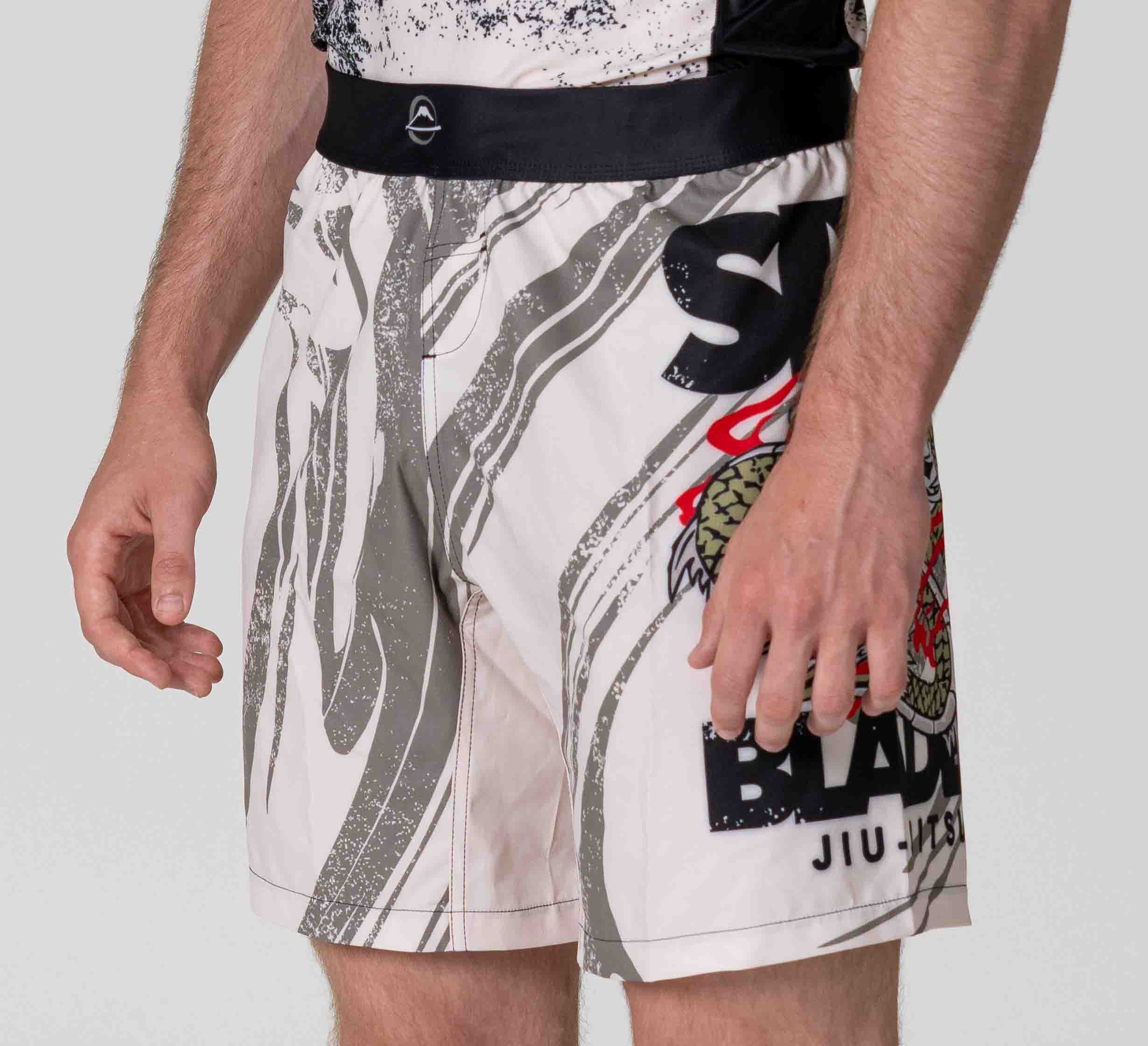Someone wearing Six Blades Dragon Flex Lite Shorts—white and gray with a black waistband, featuring colorful graphics including a snake on the right leg.