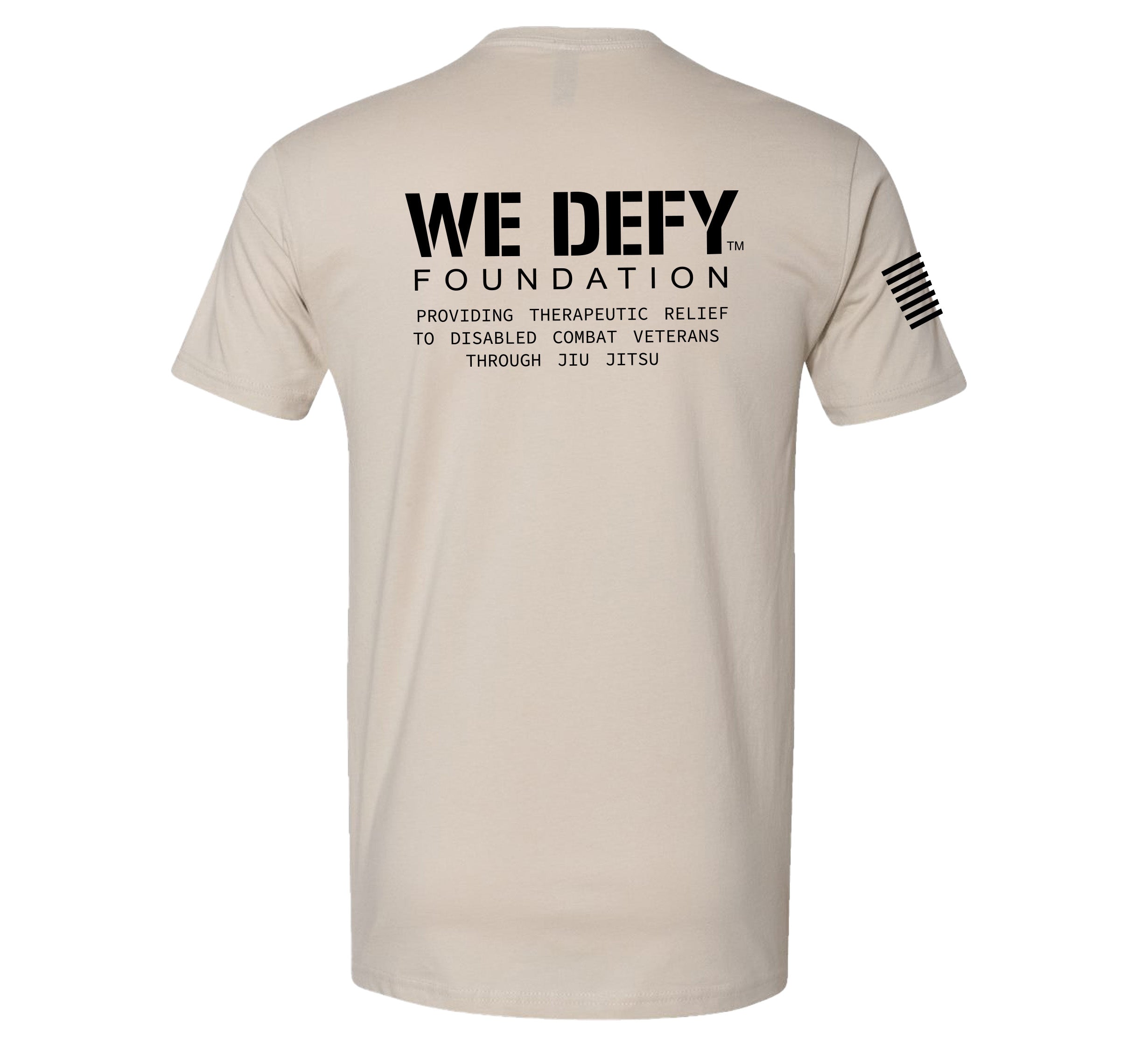 The We Defy Core T-Shirt Sand features black "WE DEFY FOUNDATION: Providing therapeutic relief to disabled combat veterans through Jiu Jitsu" text on the back and a black American flag graphic on the right sleeve.