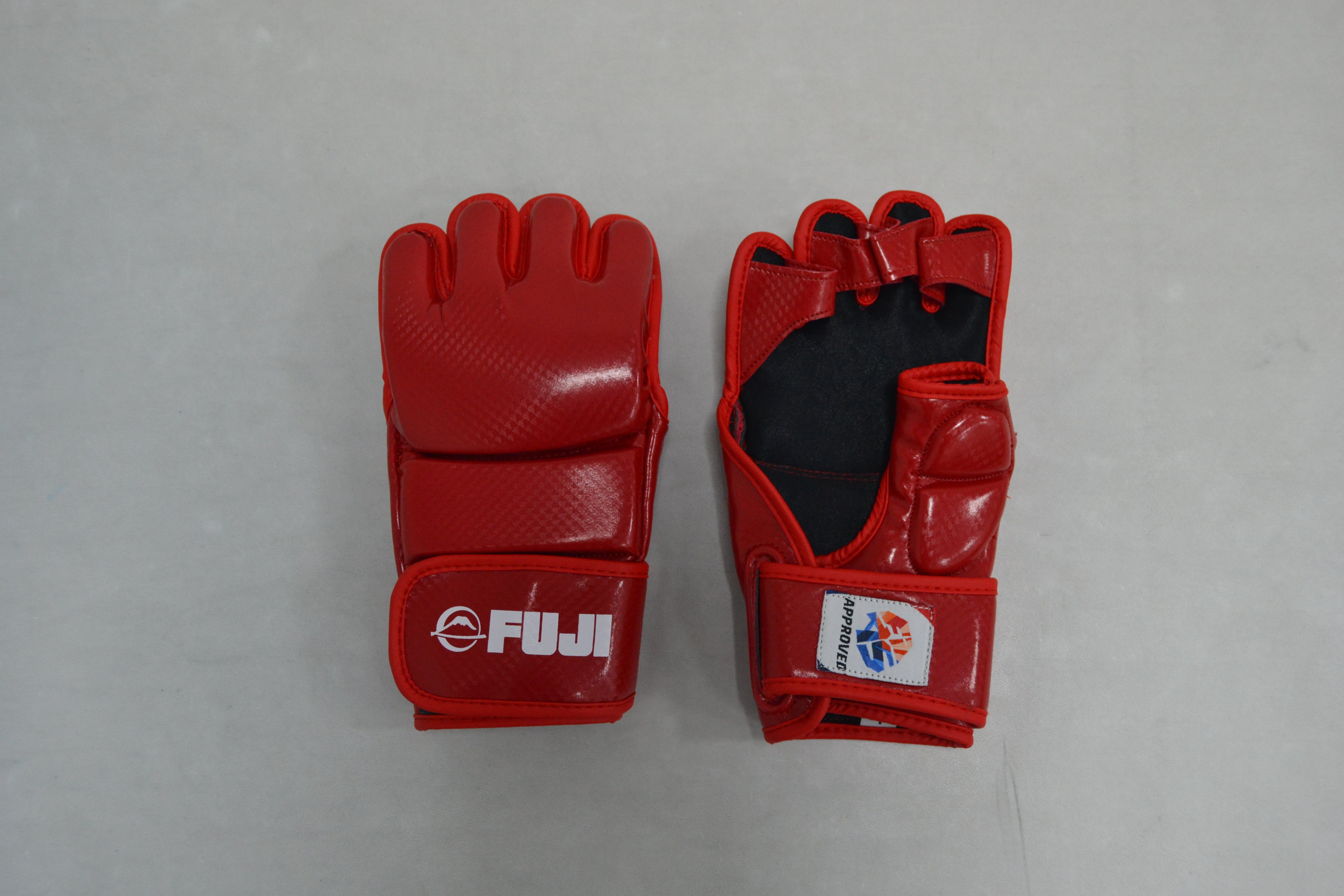 Two FIAS Sambo Combat Gloves in red are placed side by side on a gray surface. The glove on the left displays the FUJI logo, while the glove on the right shows its palm side with a patch and exposed finger holes.