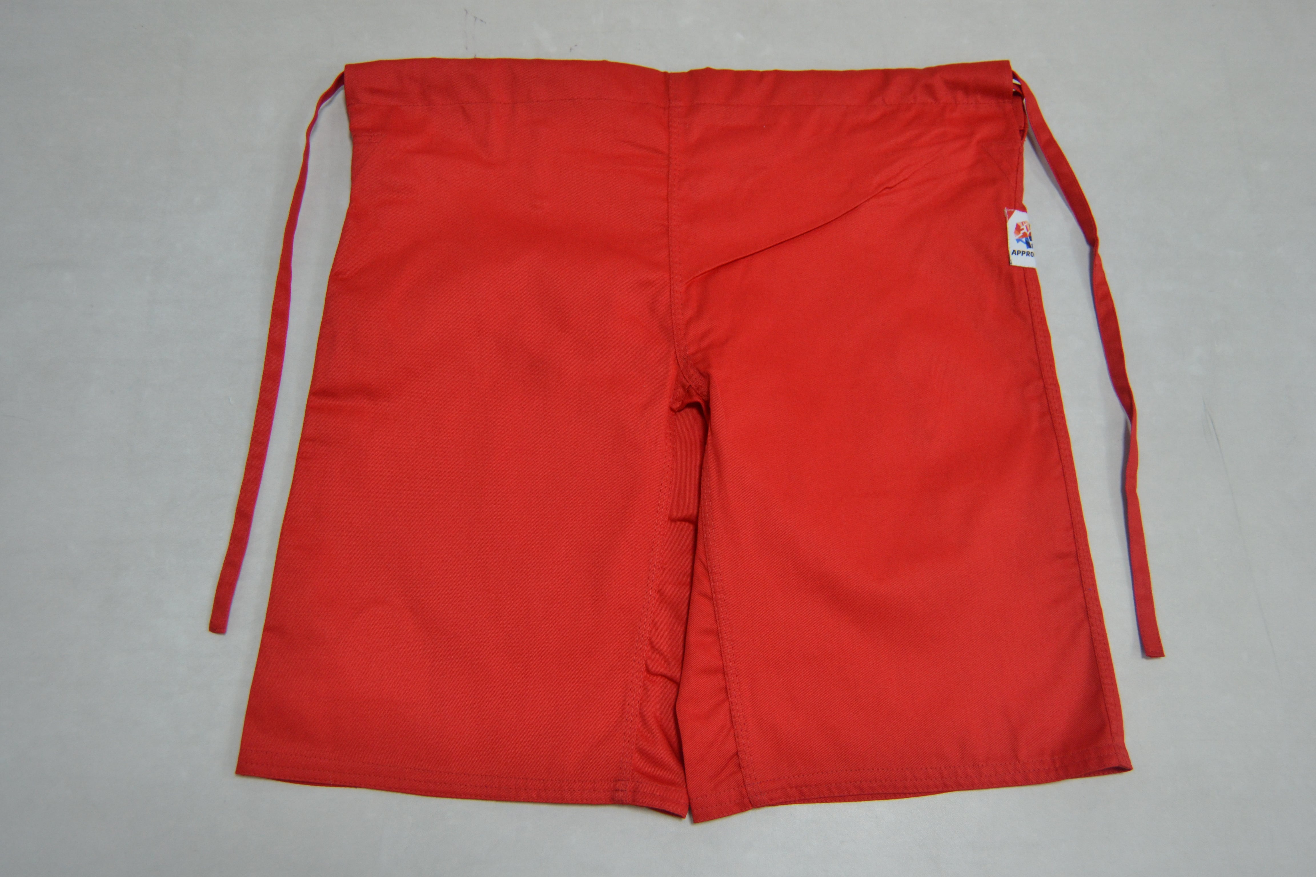 FIAS Combat Sambo Shorts Red, featuring a bright red color, knee-length cut, two long side ties, and a small white tag on the right side, are laid flat on a light surface.