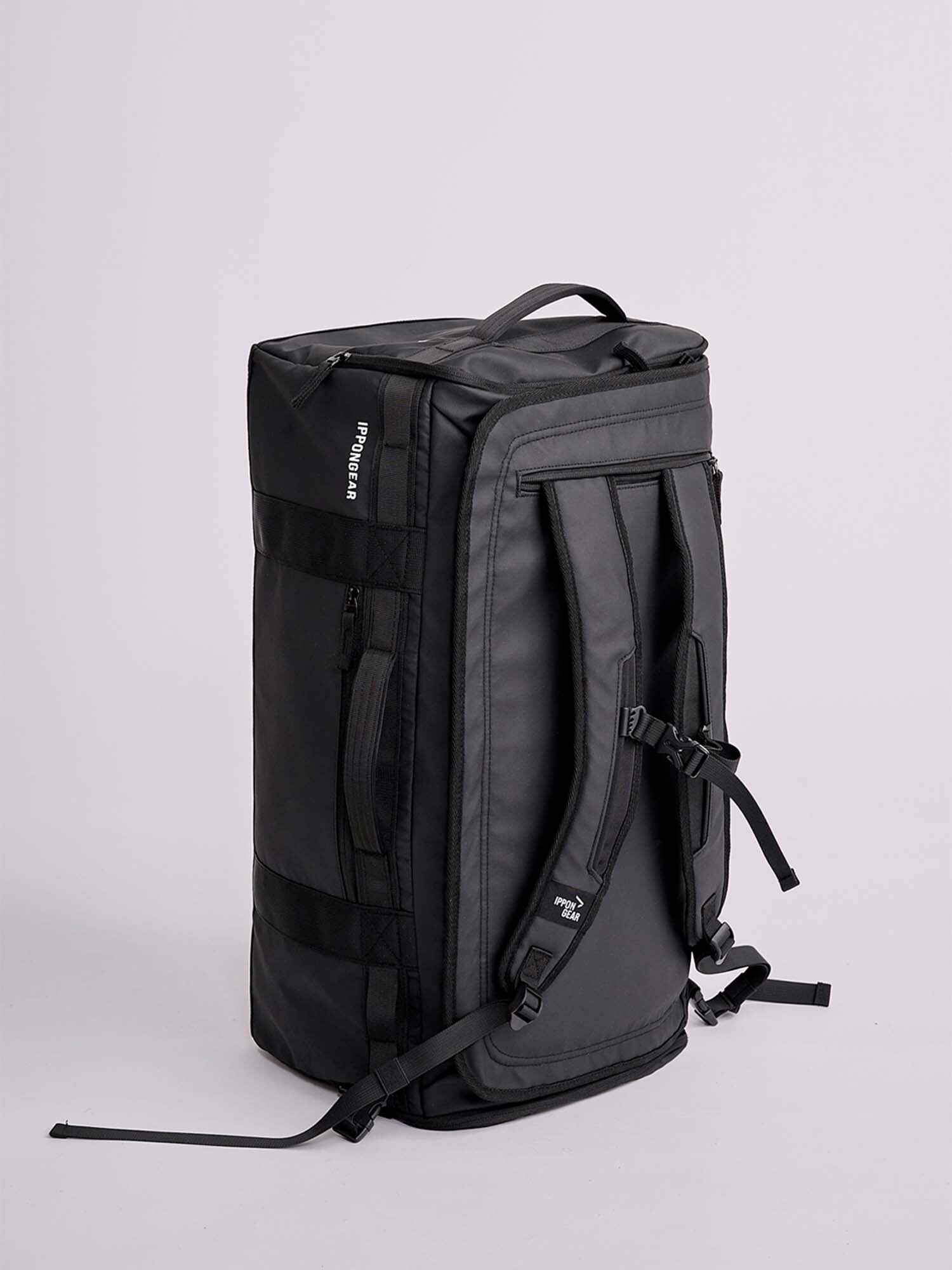 The IPPONGEAR 2 in 1 Sports Bag Black, featuring padded shoulder straps, a top handle, and multiple zippered compartments, stands upright against a plain light gray background.