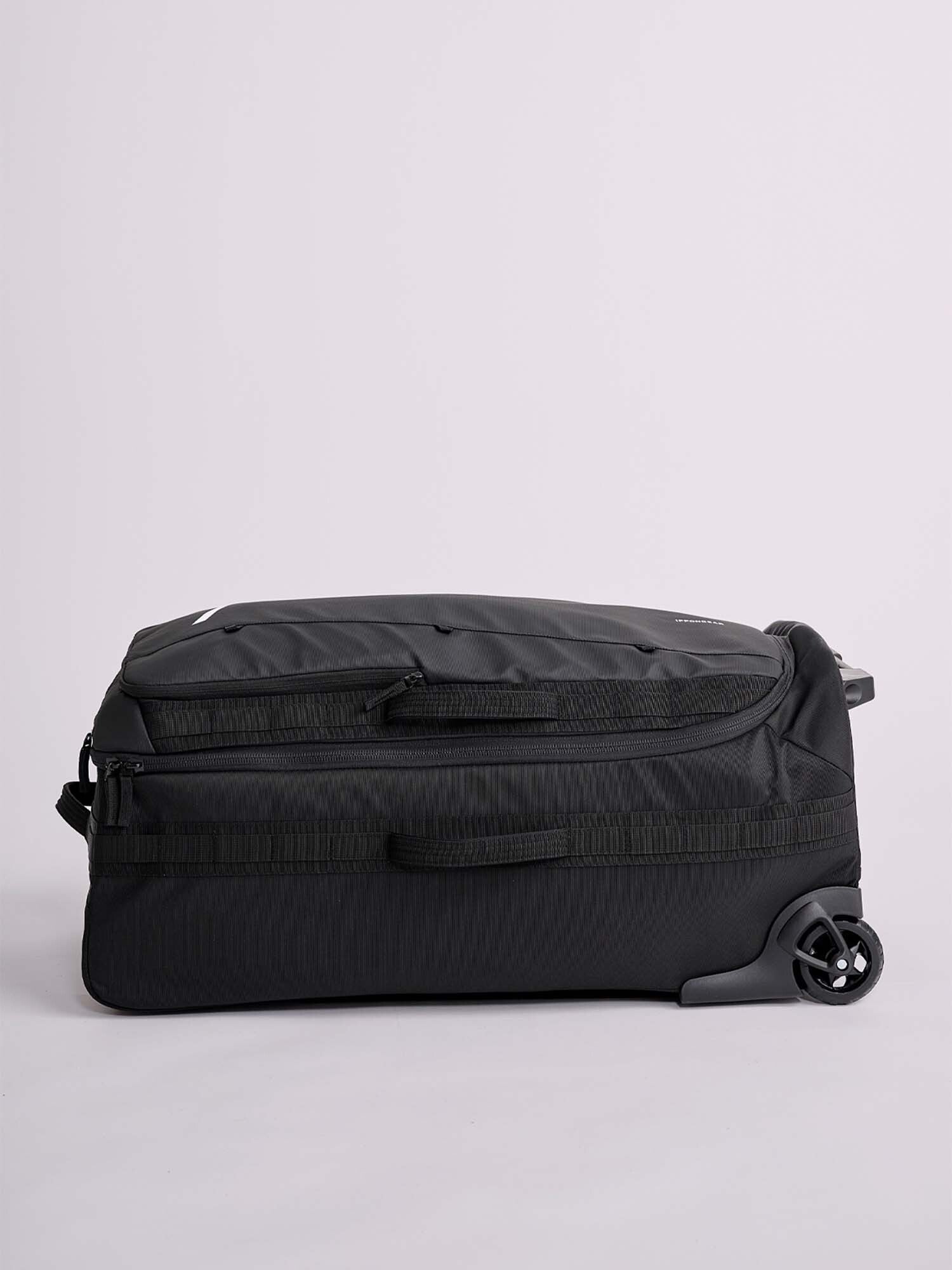 The IPPONGEAR Travel Trolley Black L lies flat on its side against a light gray background, displaying two wheels, a side handle, and a zippered side pocket.