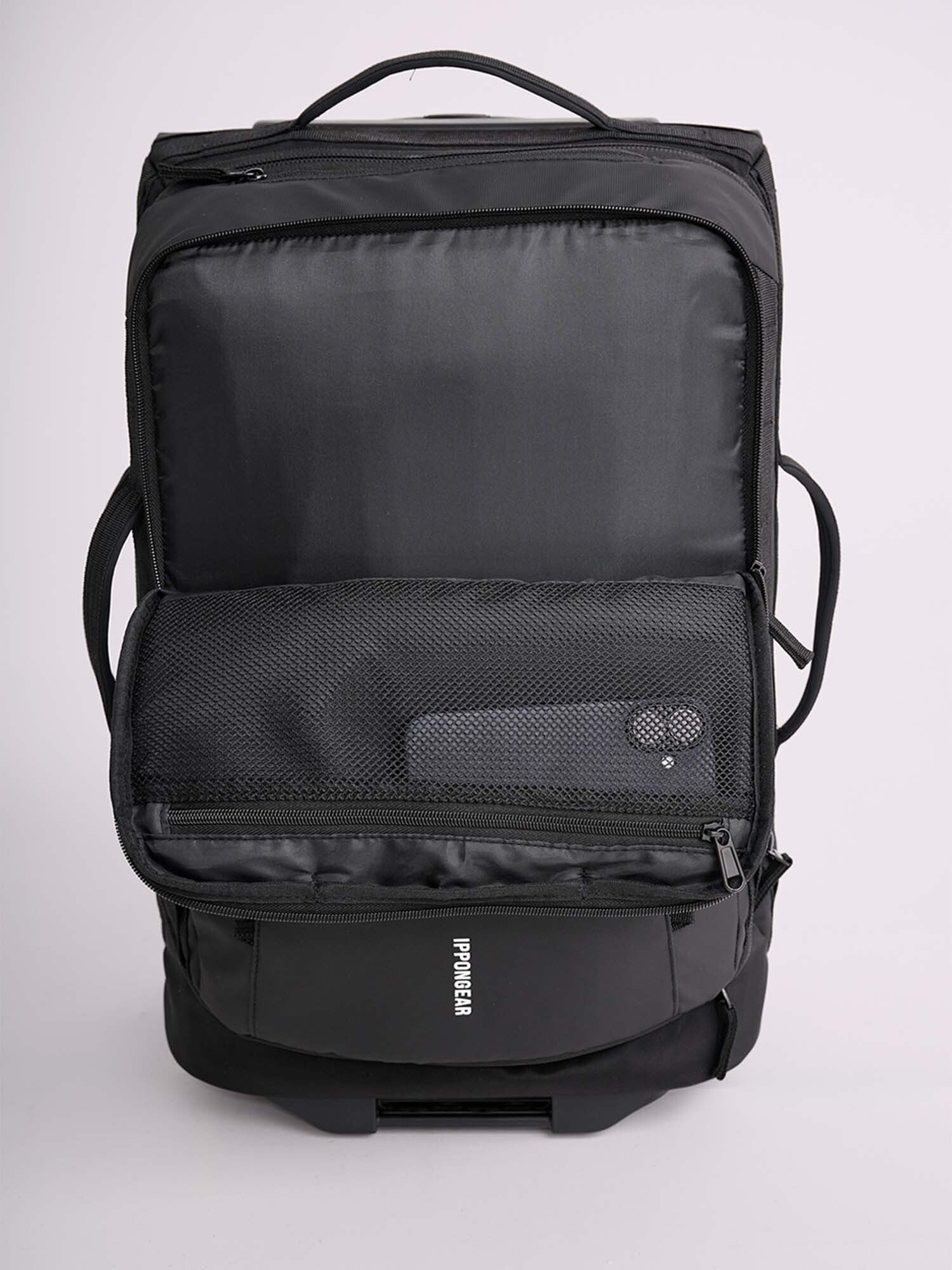 The IPPONGEAR Travel Trolley Black M is shown with its front compartment unzipped, revealing a mesh pocket holding a portable device. It features top and side handles, and the brand name is visible near the bottom.