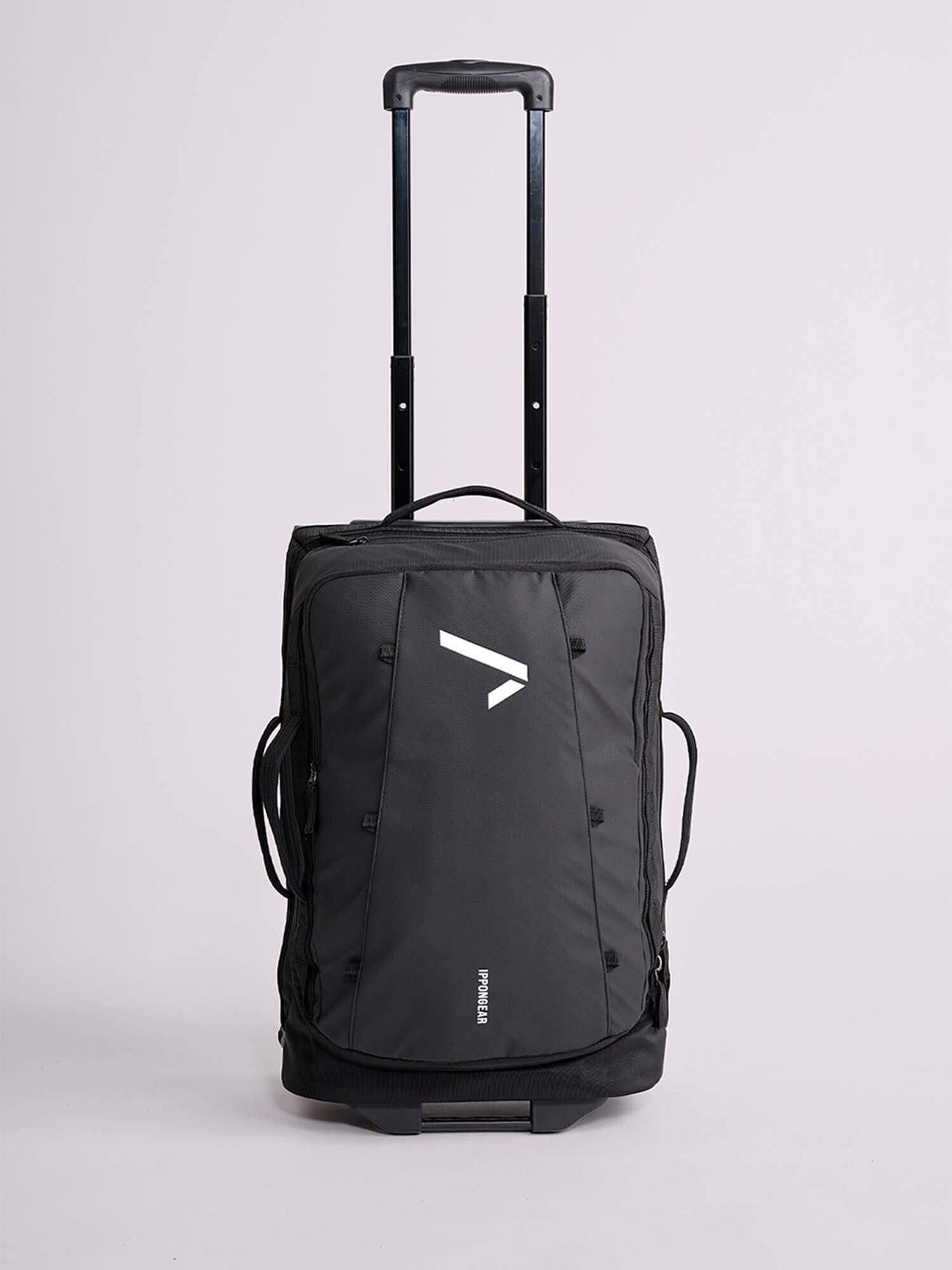 The IPPONGEAR Travel Trolley Black M is a black rolling duffel bag featuring a telescopic handle, side handles, and a white geometric logo on the front, shown against a plain light background.