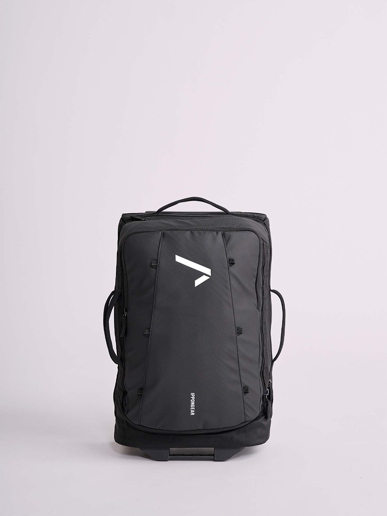 The IPPONGEAR Travel Trolley Black M is a black travel backpack with a white geometric logo on the front, featuring a top handle and side handles, shown upright against a plain light background.