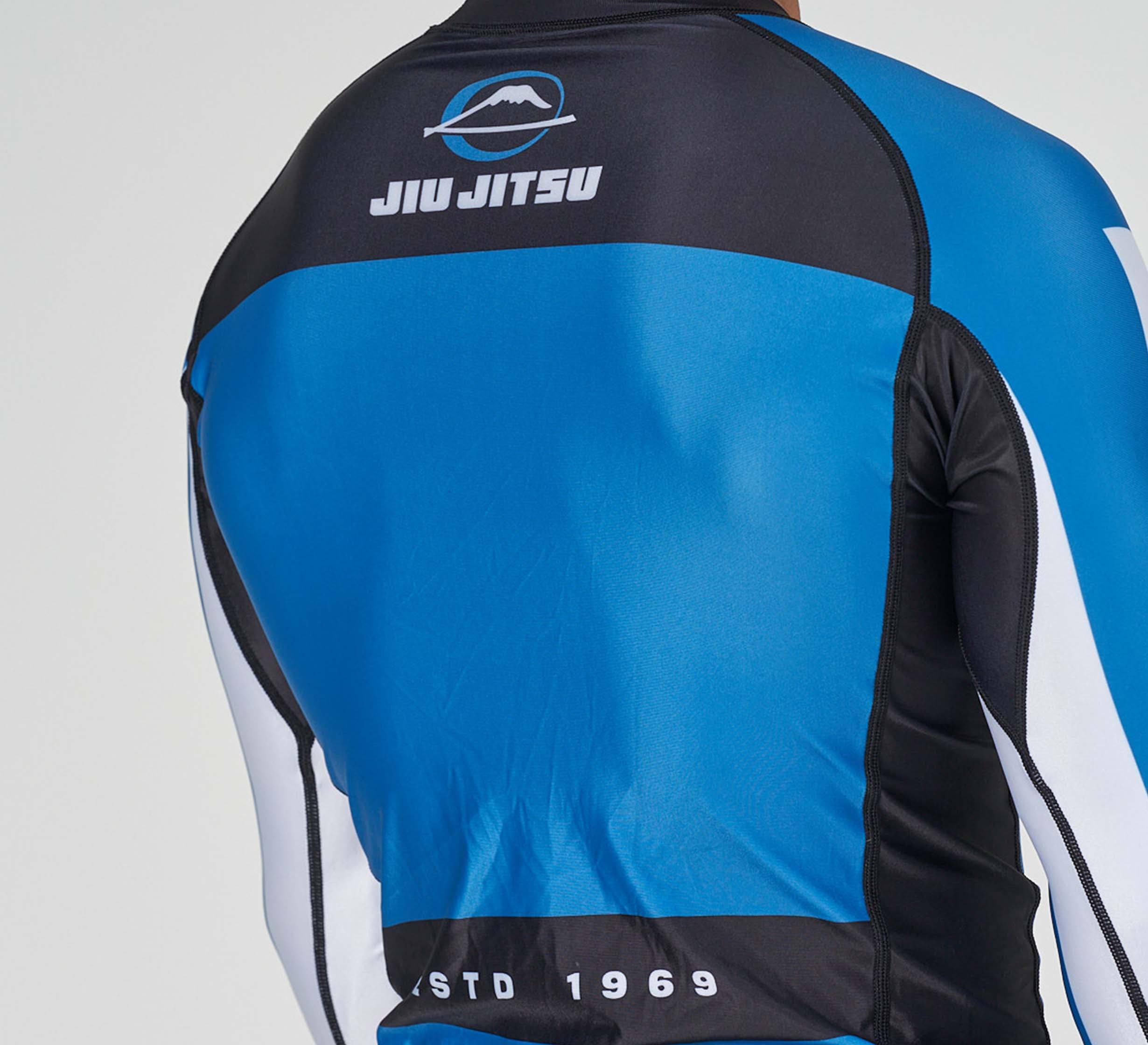 A person wearing the Jiu Jitsu Script Flex Lite Long Sleeve Rashguard in blue.