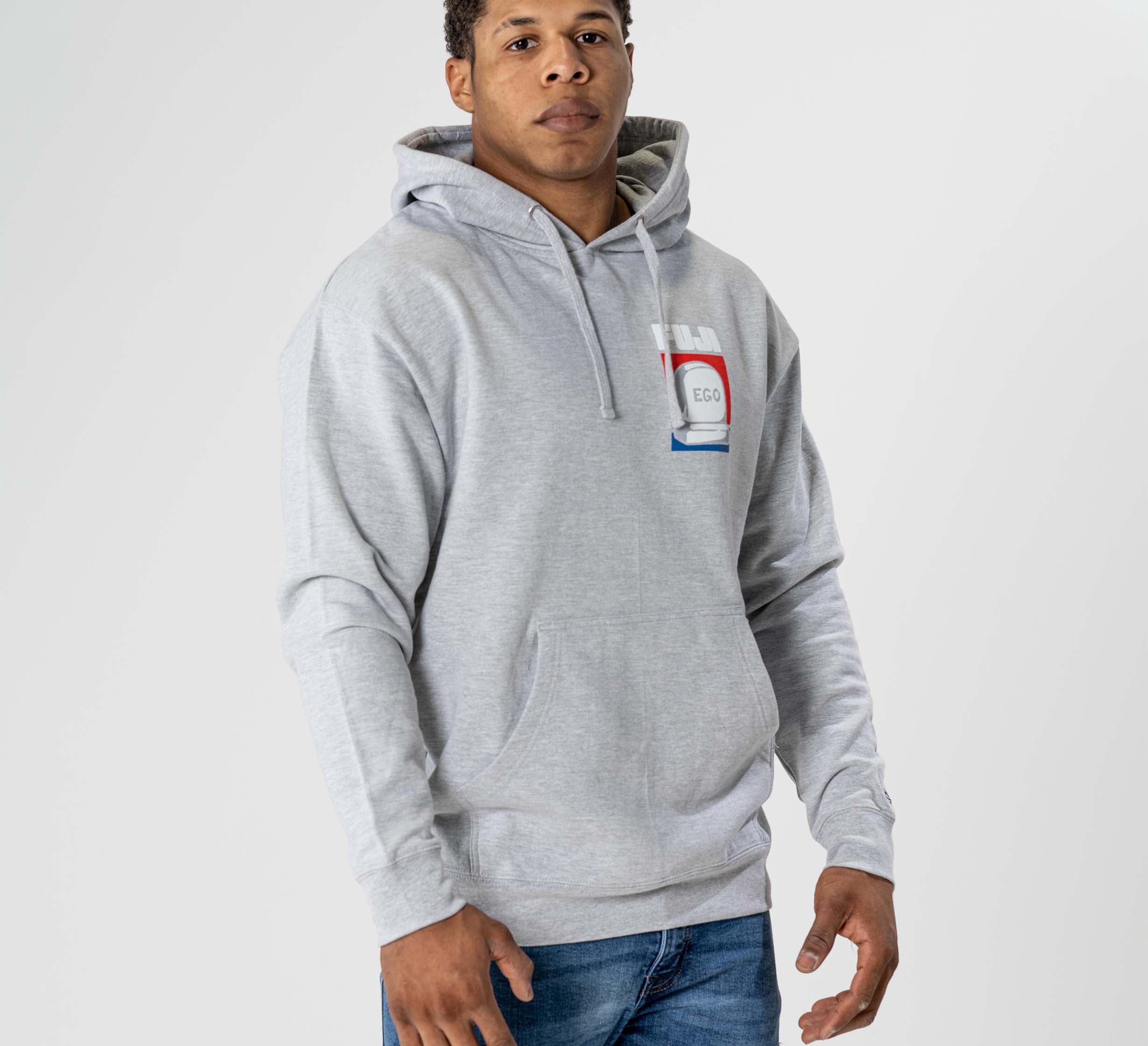 A man wears the Submit Your Ego Hoodie in heather grey, featuring a front pocket and a red, white, and blue "EGO" graphic on the chest, paired with blue jeans against a plain white background.