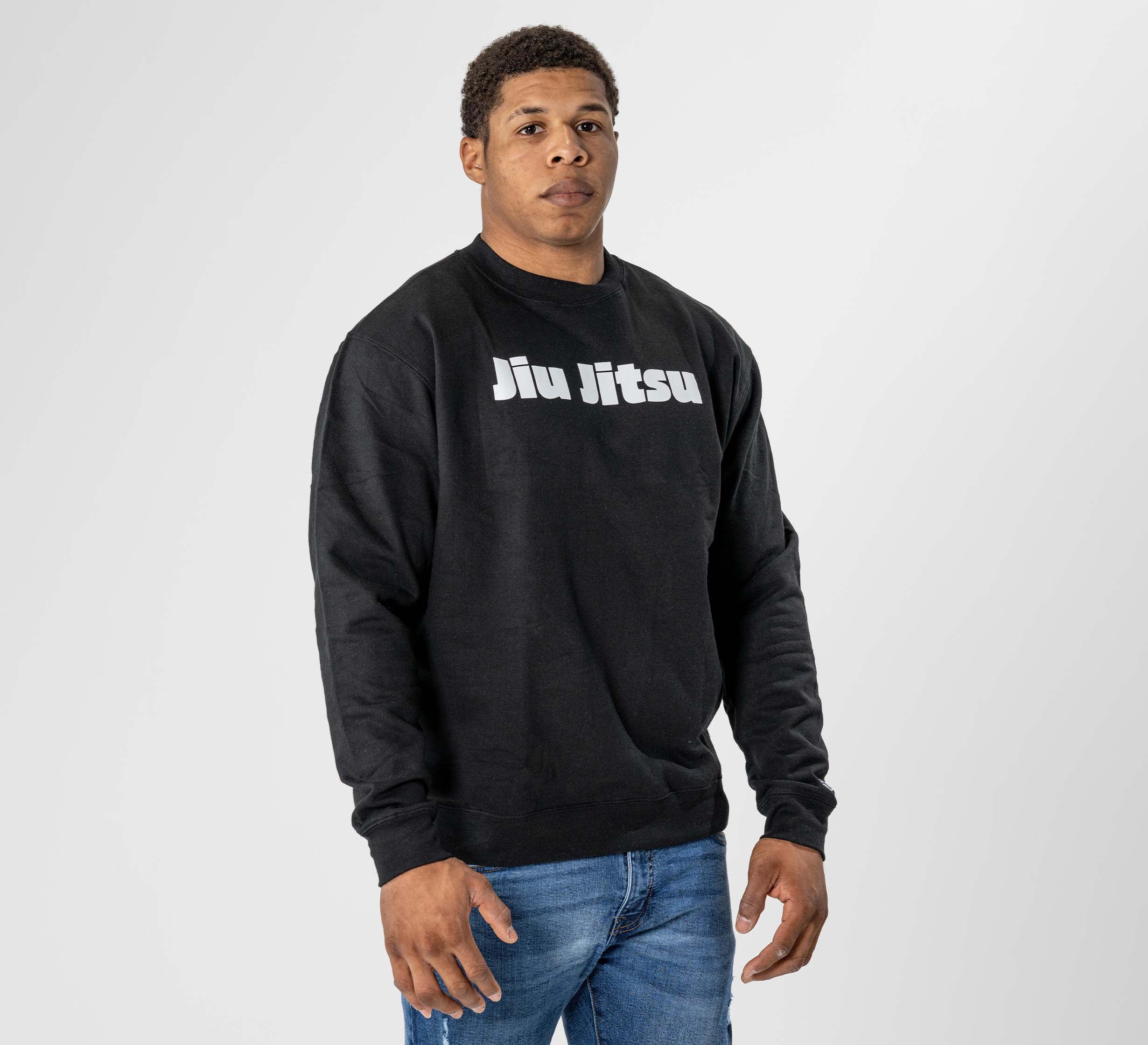 A person models the Jiu Jitsu Player Crewneck Black, featuring a white "Jiu Jitsu" print, against a plain light gray background while looking directly at the camera with a neutral expression.