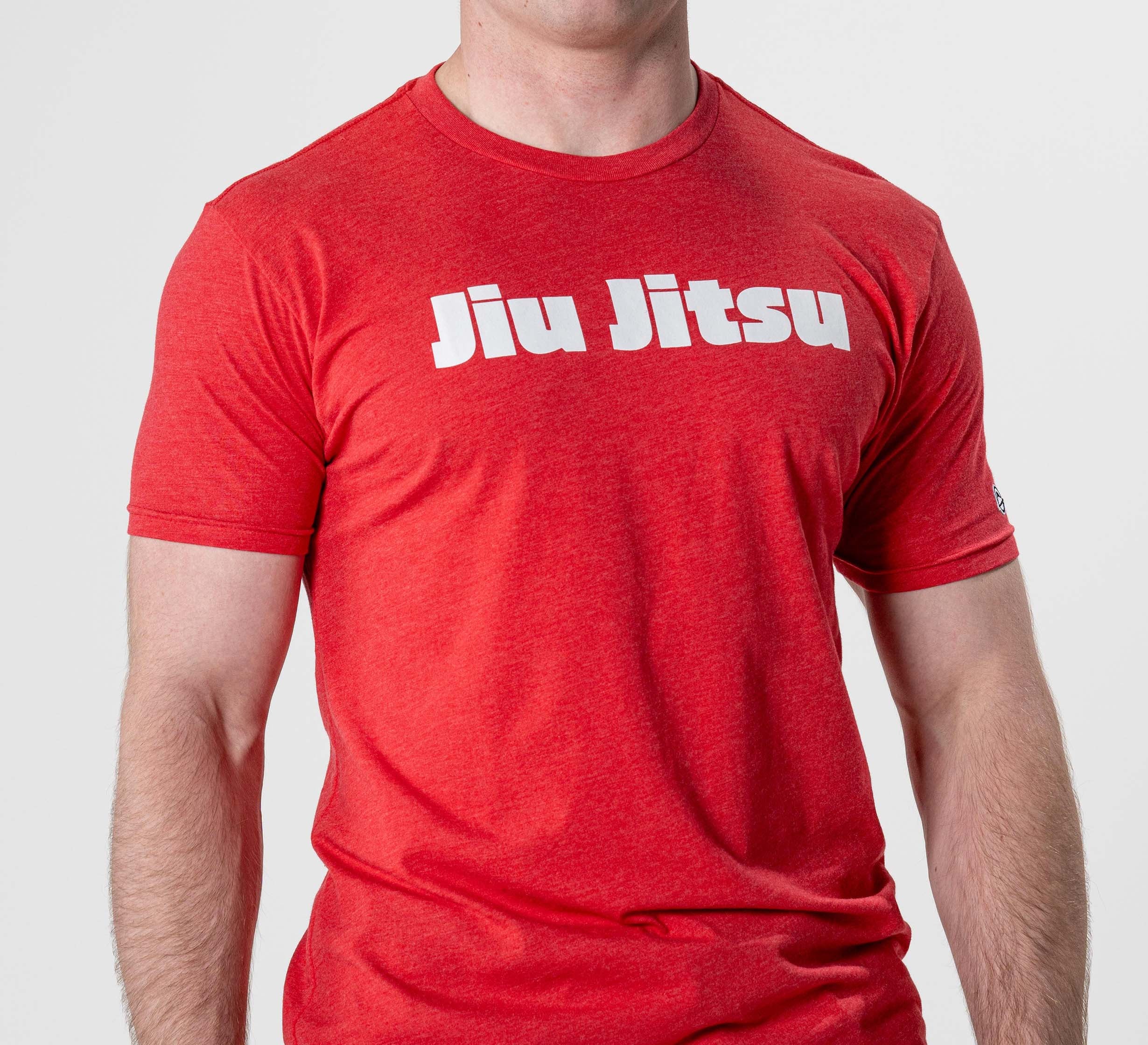 Someone wearing the Jiu Jitsu Player T-Shirt Red, featuring bold white "Jiu Jitsu" lettering across the chest, stands against a plain light background.