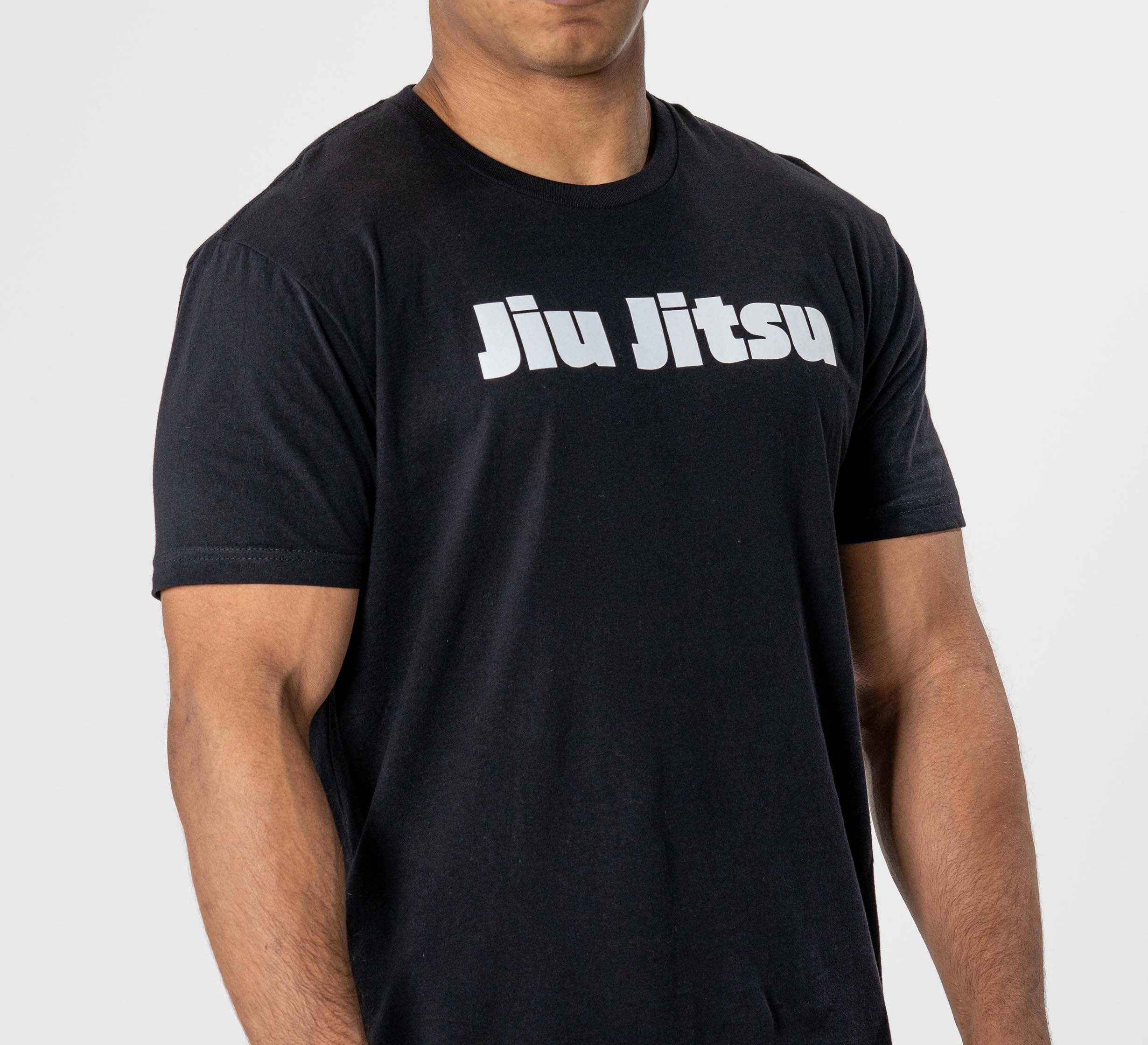 A person shown from shoulders to waist wears the Jiu Jitsu Player T-Shirt Black, featuring "Jiu Jitsu" in bold white letters across the chest, set against a plain background.