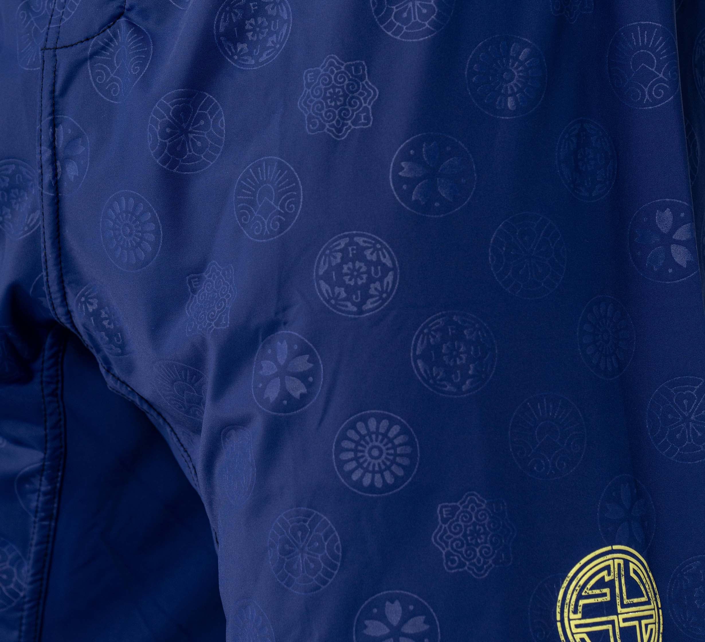 Close-up of Shogun Heat Gear Shorts Navy: dark blue fabric with a subtle pattern of circular floral and geometric motifs. A gold circular design appears in the lower right corner.