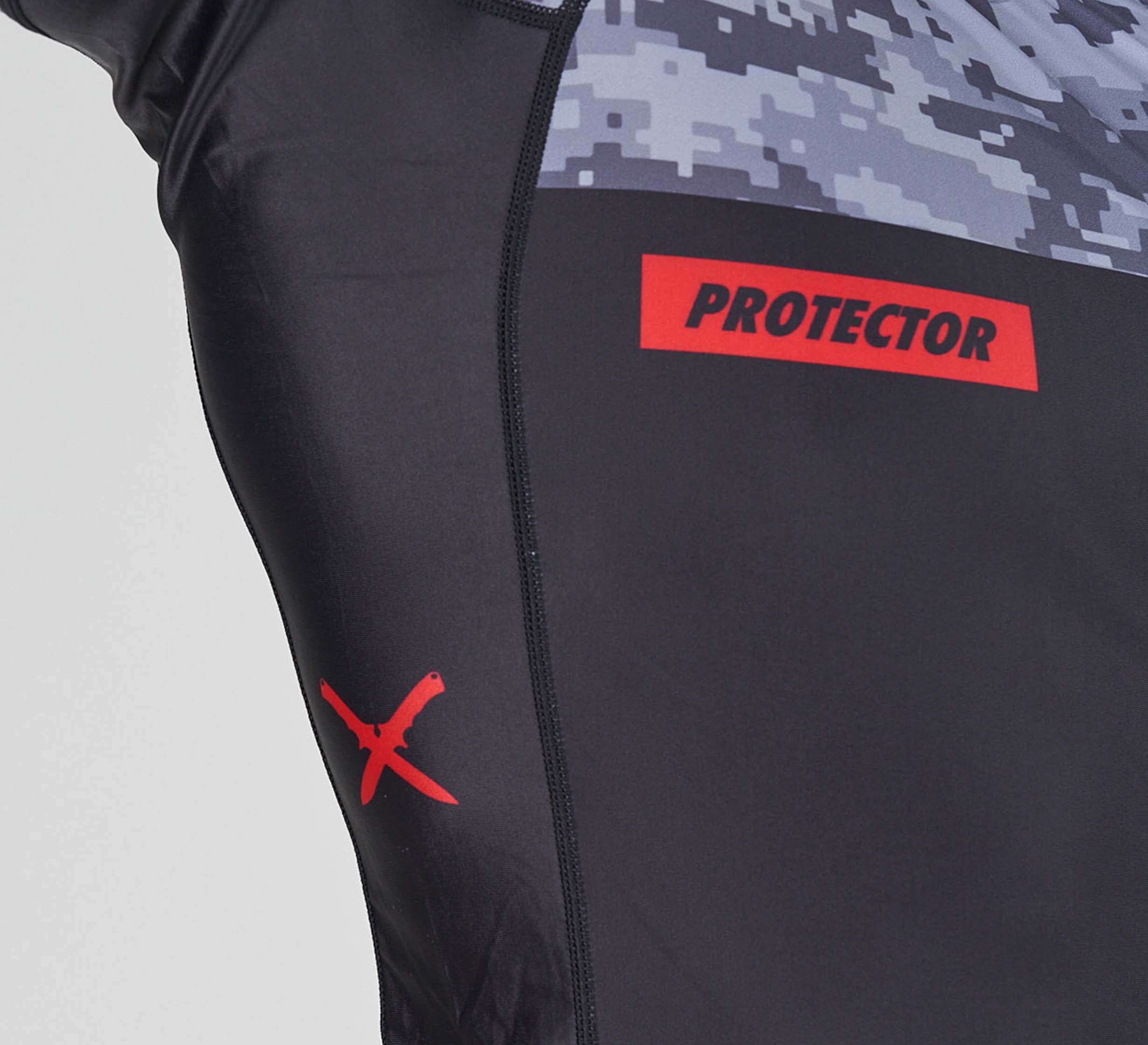Close-up of the Sheepdog Response Flex Lite Rashguard Black, featuring a digital camo top, a red X on the side, and "PROTECTOR" in bold red on a rectangular patch.