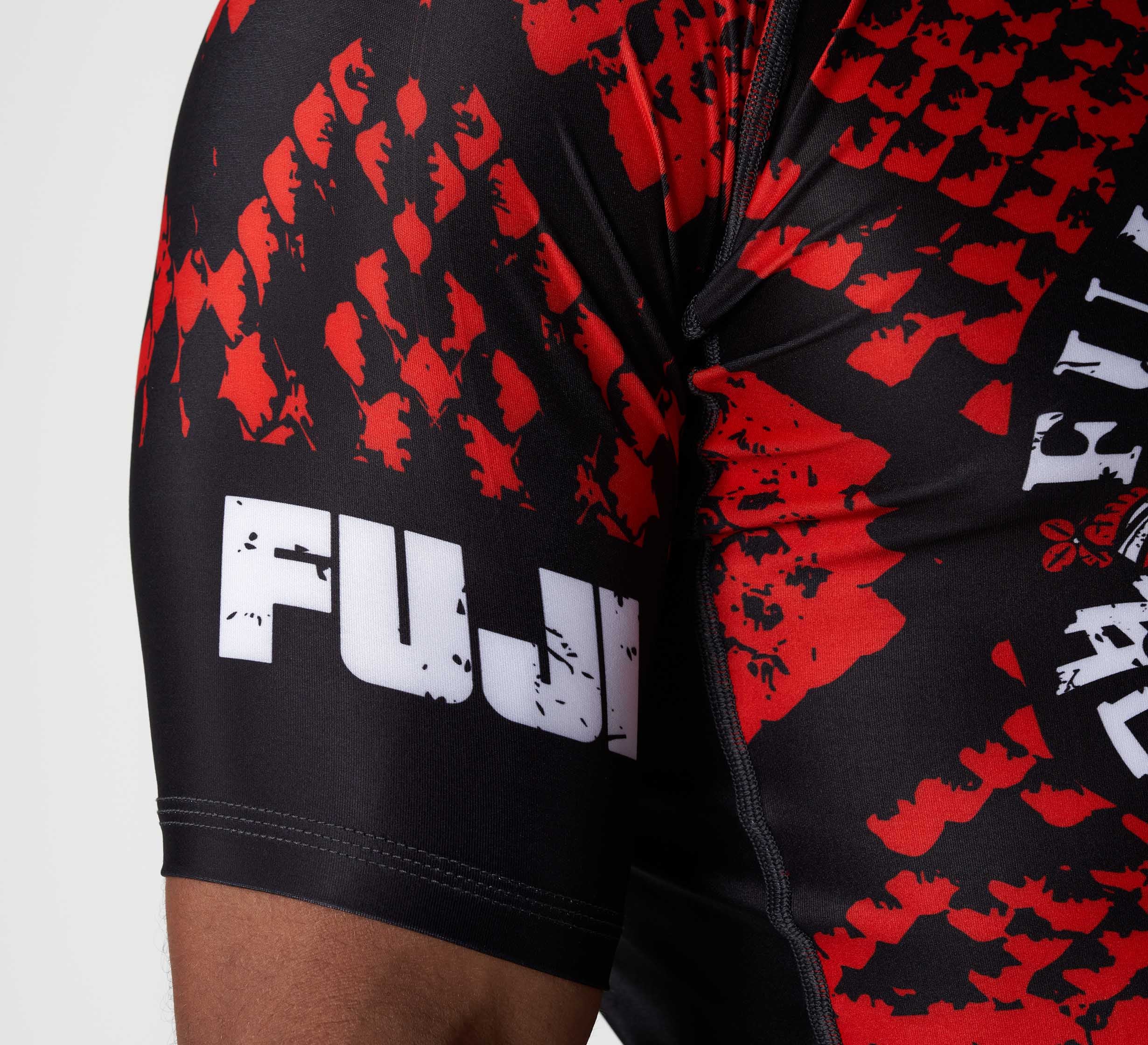 Close-up of a person wearing the Oni vs. Anaconda Short Sleeve Rashguard Red, featuring a bold red pattern and a white FUJI logo on the sleeve.