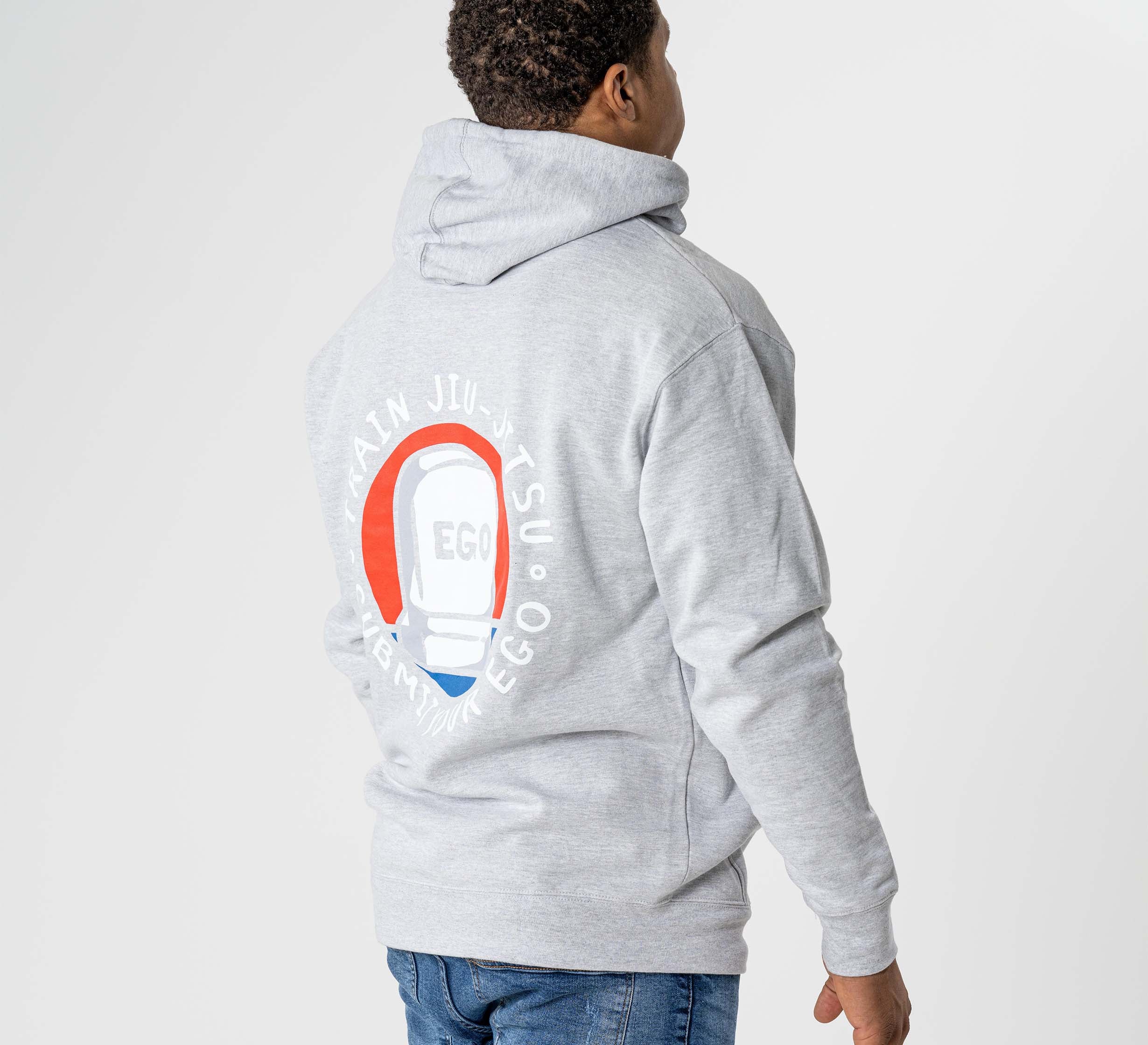 A man stands with his back to the camera, wearing the Submit Your Ego Hoodie in heather grey featuring a circular red, white, and blue EGO graphic on the back, set against a plain white background.