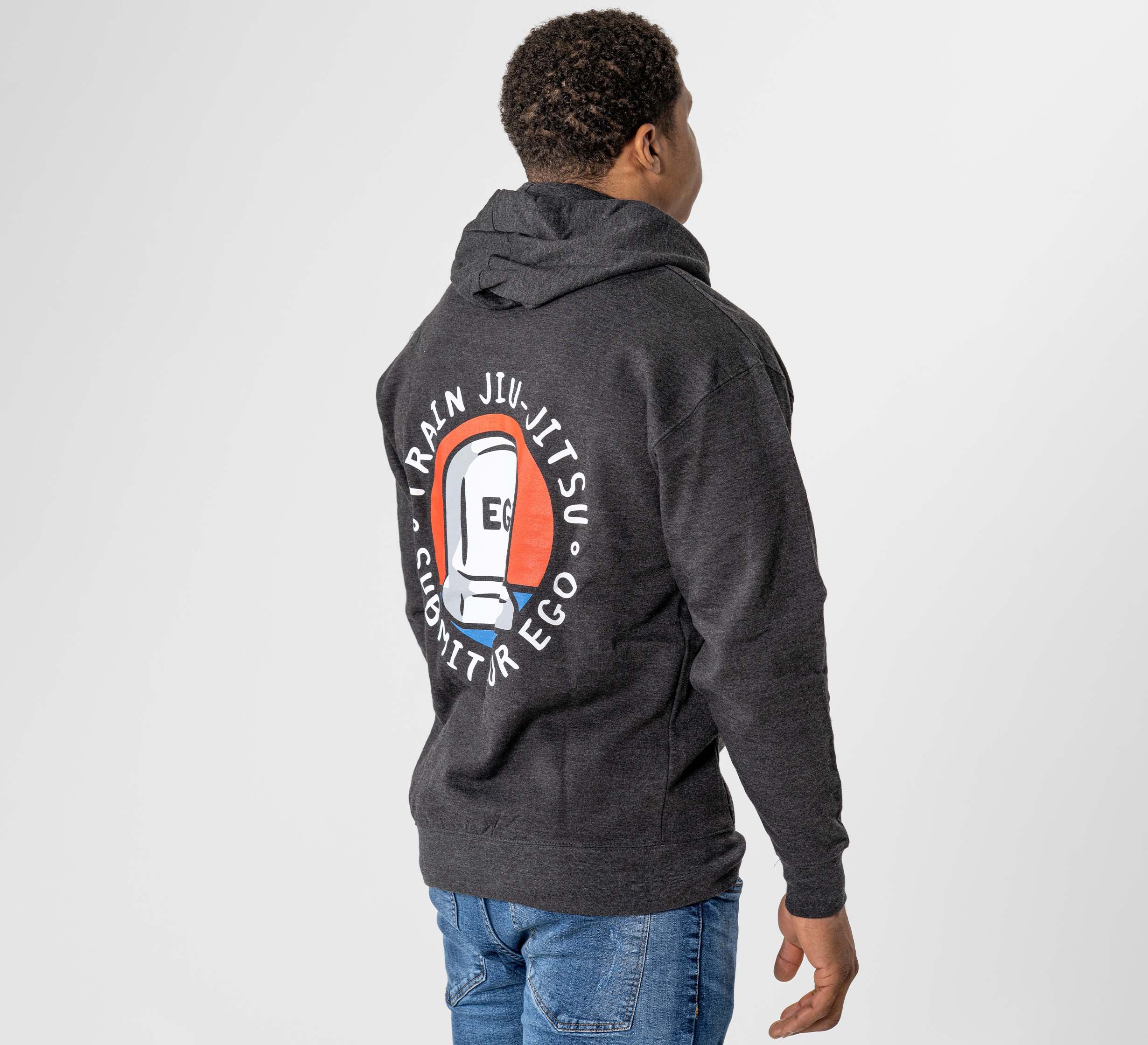 A man faces away from the camera, wearing the Submit Your Ego Hoodie in heather black. The hoodie features a large back graphic of a jiu-jitsu belt and the words "TRAIN JIU JITSU • SUBMIT YOUR EGO" in a circular design.