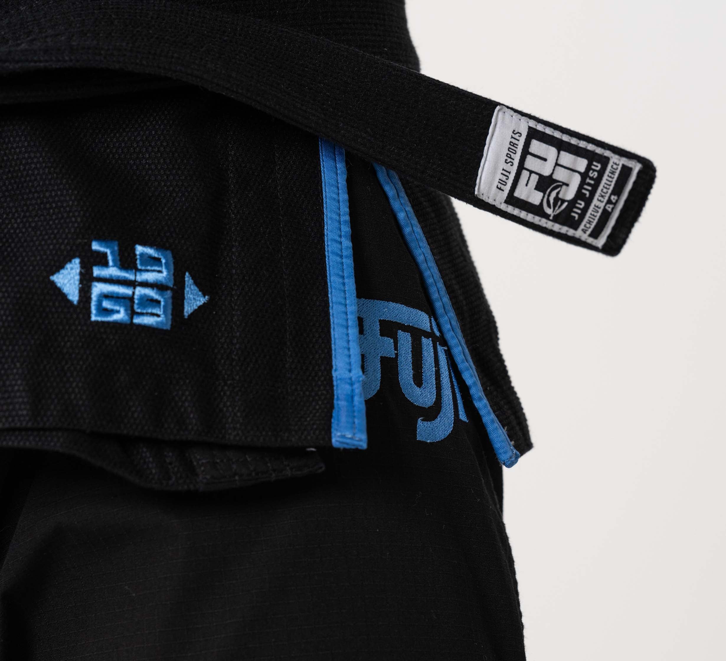 Close-up of the Flow-Tech BJJ Gi in black with blue trim and embroidery, featuring a FUJI patch on the belt and details of the jacket and pants.