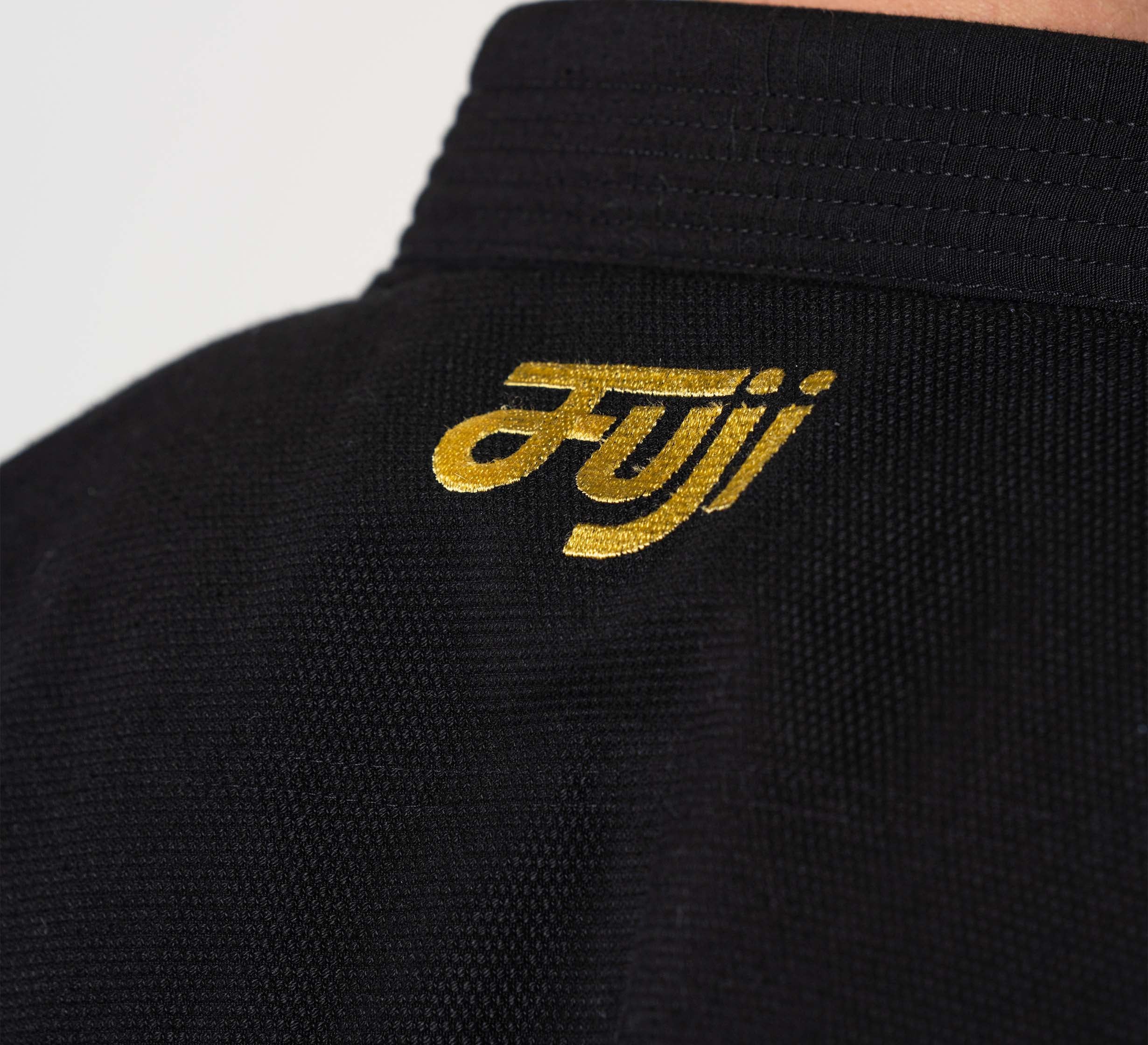 Close-up of the back of the Flow-Tech BJJ Gi Black/Gold with "Fuji" embroidered in yellow on the collar.