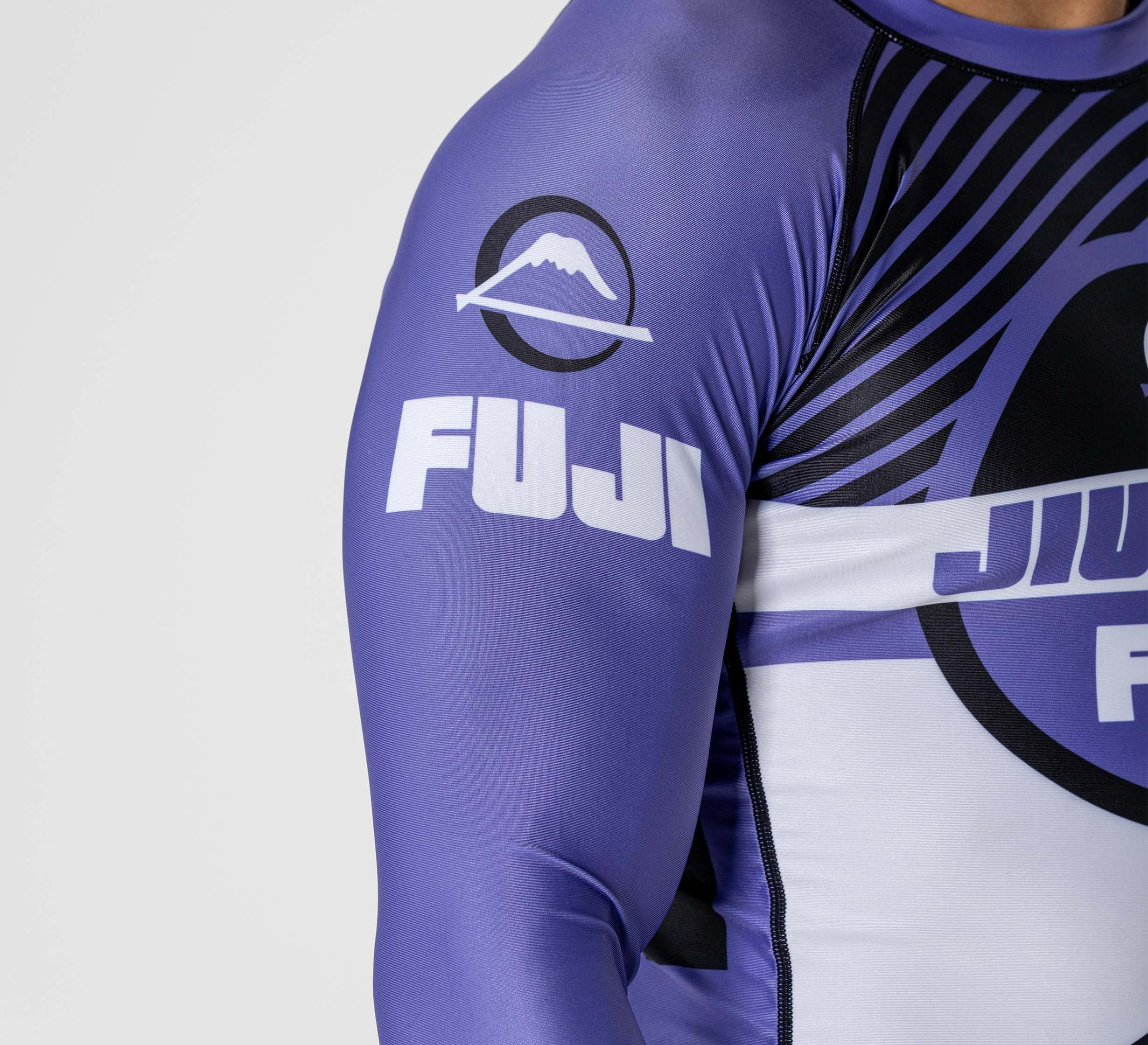 A close-up of a person wearing the Pacer Flex Lite Long Sleeve Rashguard Purple, featuring the FUJI brand logo and a mountain graphic on the sleeve.