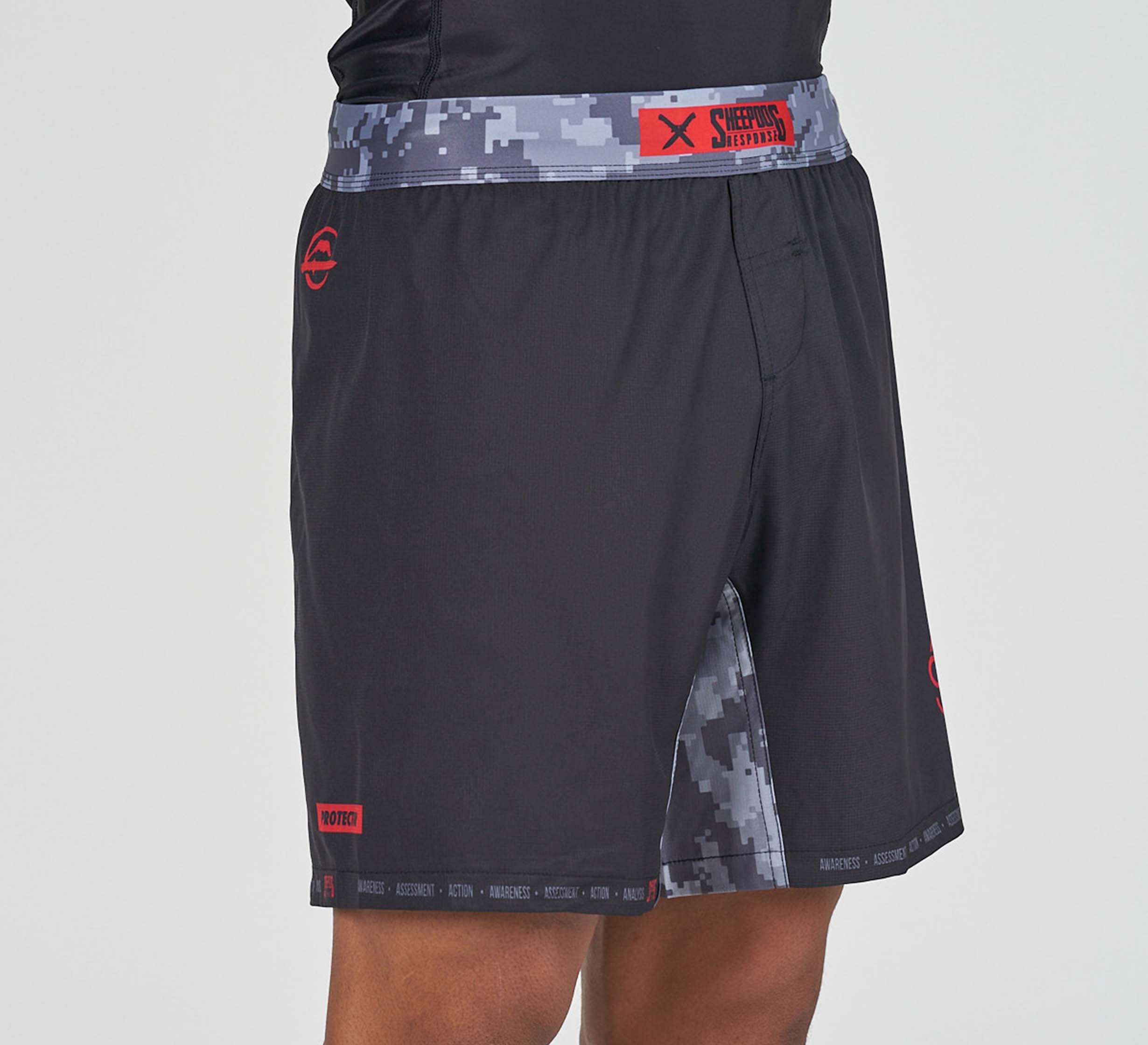 A person wearing Sheepdog Response Flex Lite Shorts Black, featuring a digital camouflage waistband and inner leg panels with red logos and text accents.