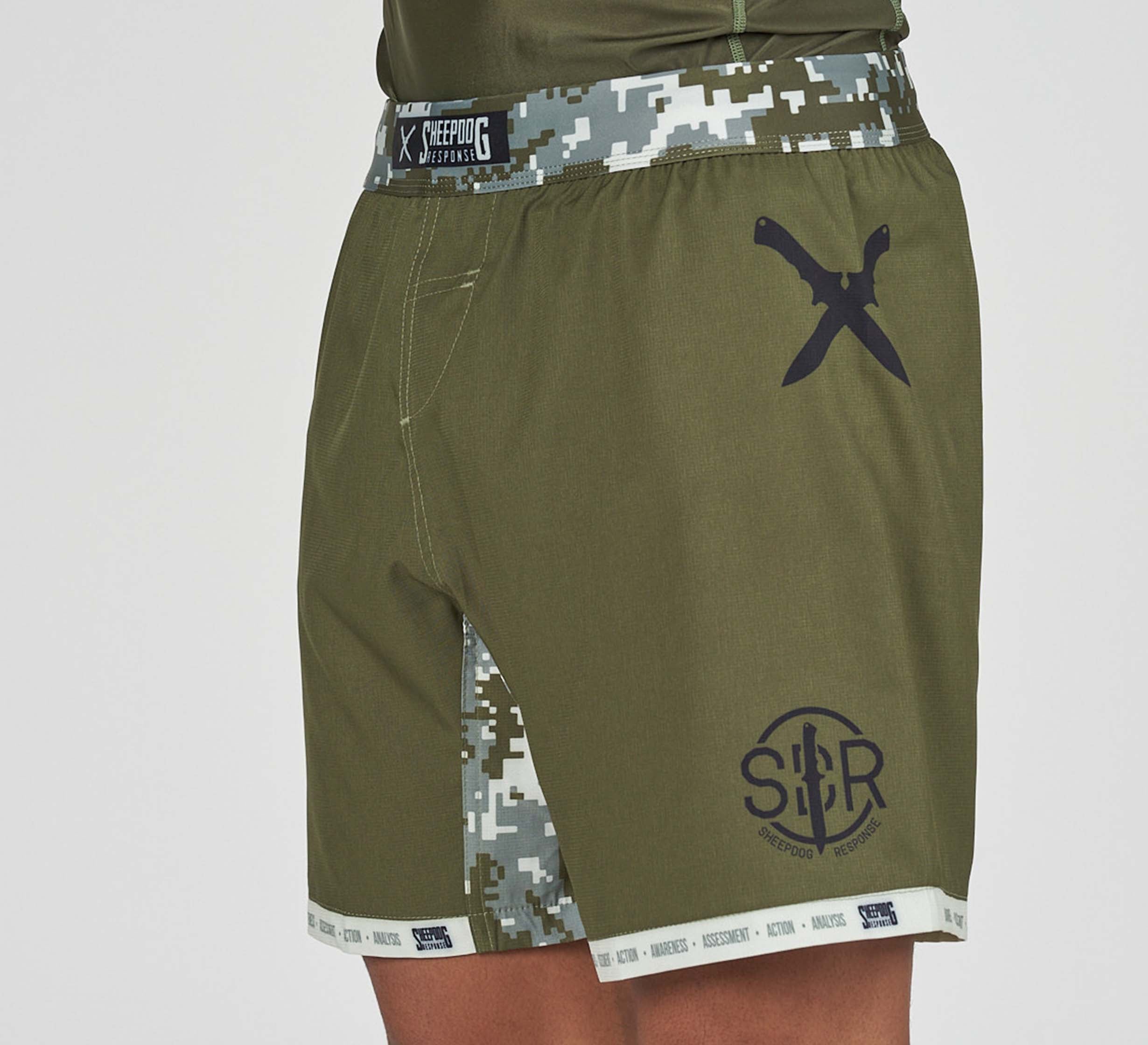 The Sheepdog Response Flex Lite Shorts in Military Green feature a digital camo side panel, black knife graphic on the left hip, SBC logo on the lower left leg, branded waistband, and a front pocket.