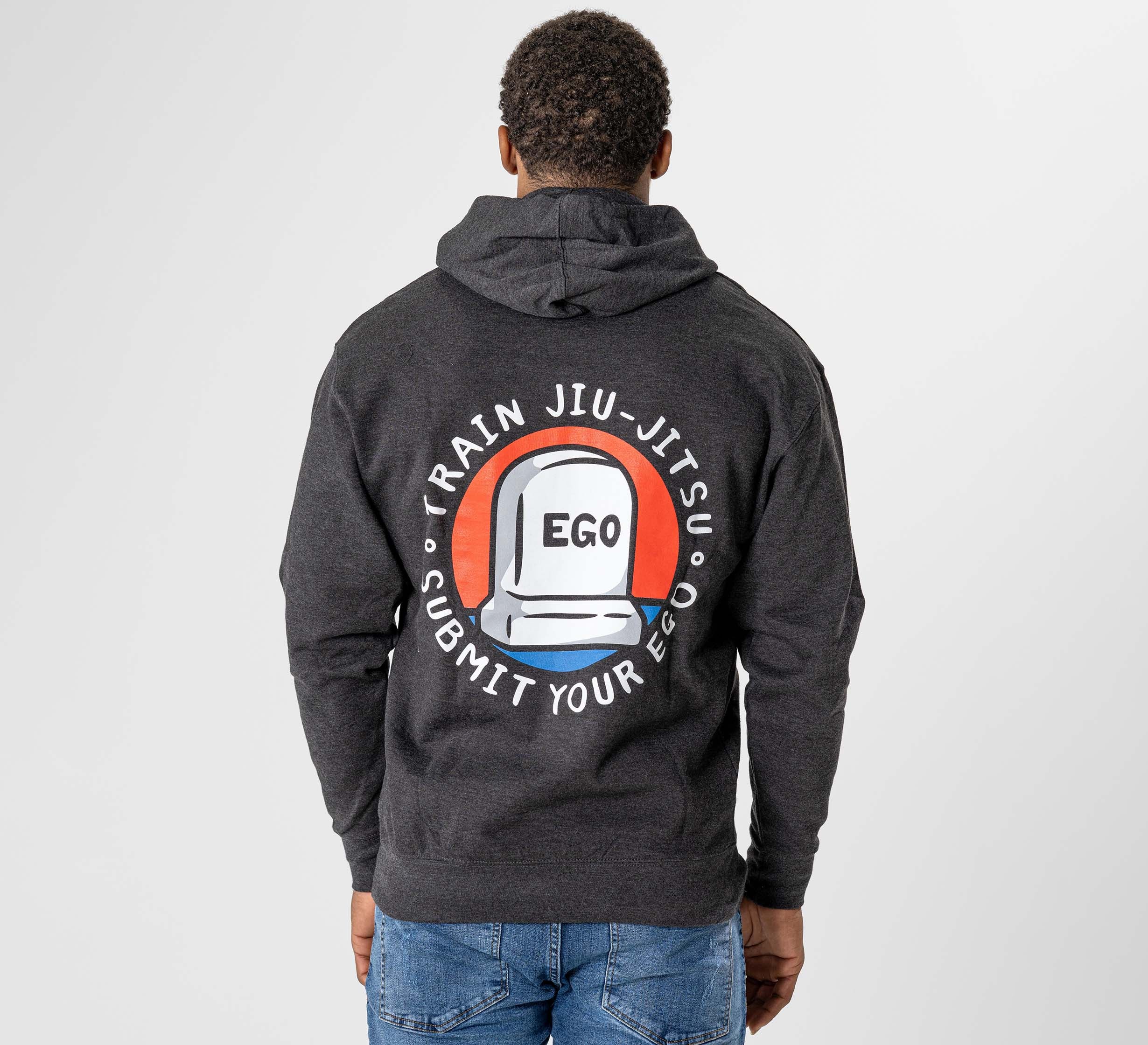 Someone wearing the Submit Your Ego Hoodie Heather Black, featuring a back design of a white helmet labeled "EGO" with "Train Jiu-Jitsu, Submit Your Ego" encircling it.