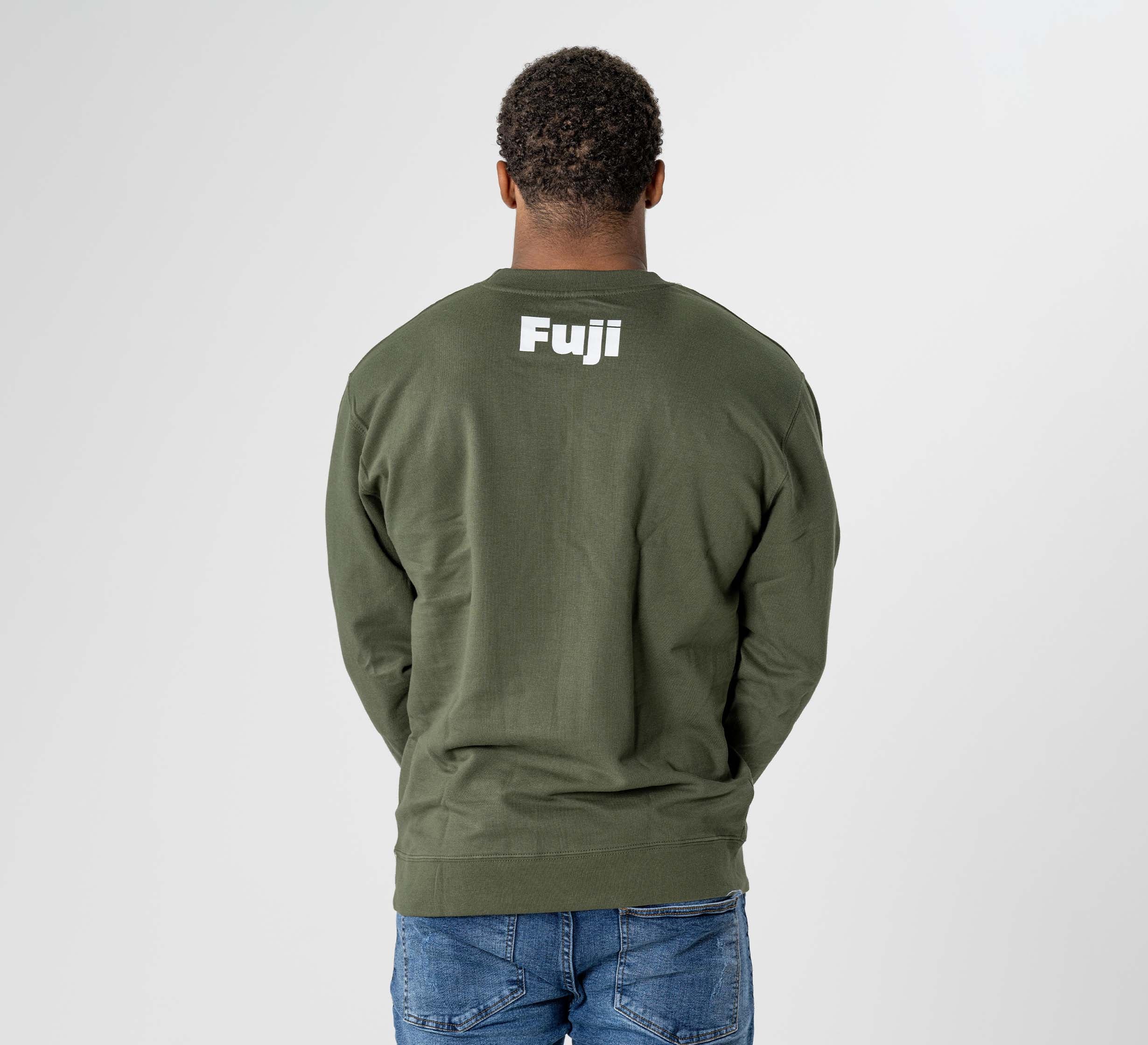 A person wears the Jiu Jitsu Player Crewneck in military green, featuring "Fuji" in white on the back, standing with their back to the camera, hands in pockets, paired with blue jeans against a plain light background.
