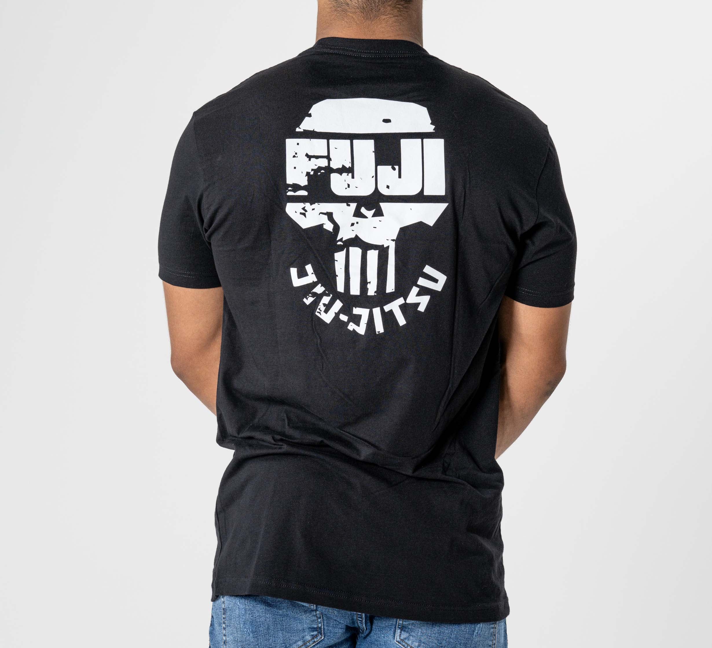 A person wears the Punishment T-Shirt Black, featuring a white "FUJI JIU JITSU" graphic and stylized design on the back, standing with arms relaxed and facing away from the camera.