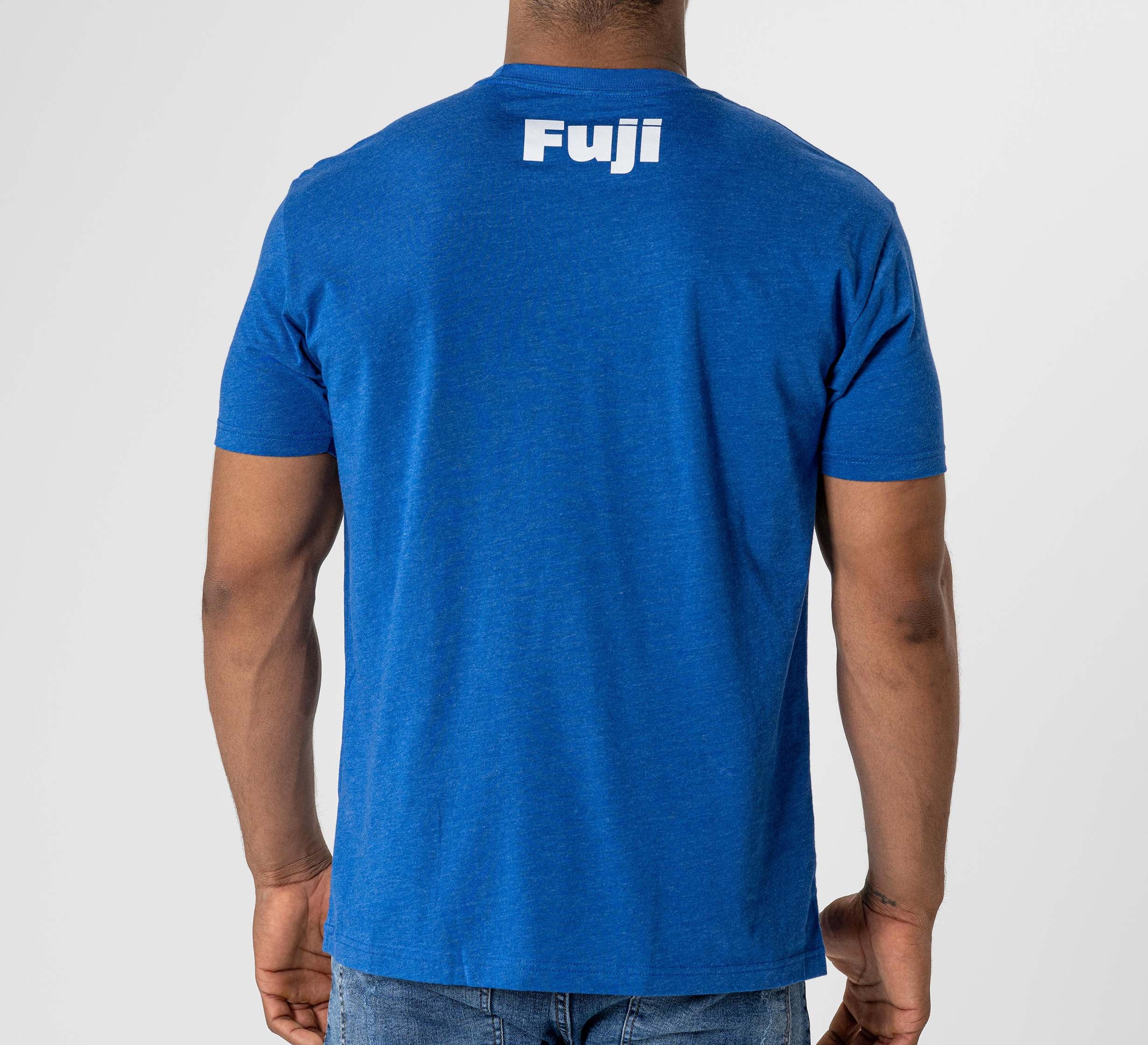 A person wearing the Jiu Jitsu Player T-Shirt Blue, featuring "Fuji" printed in white on the upper back, stands against a plain light background.