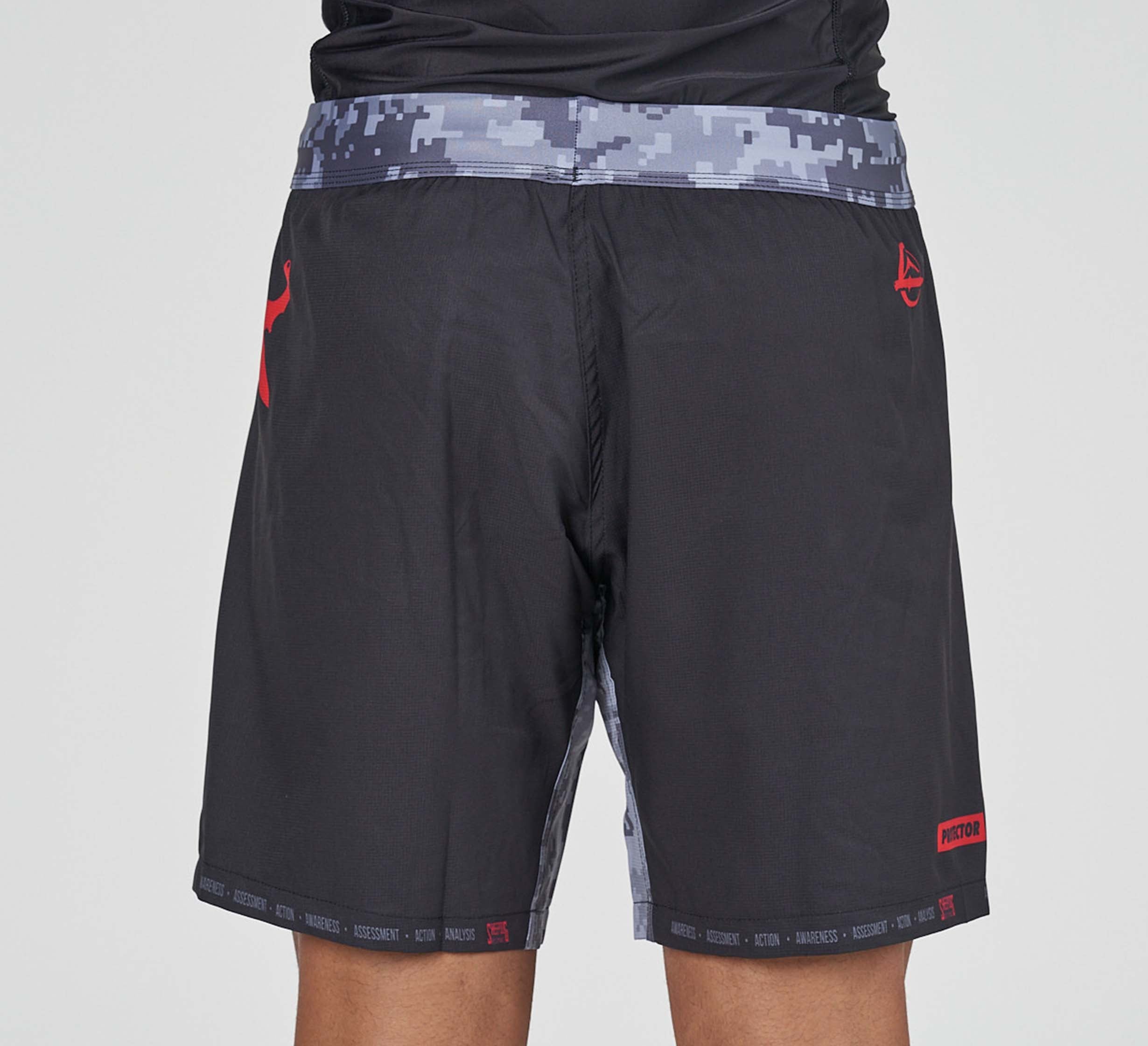A person is shown from the back wearing Sheepdog Response Flex Lite Shorts Black, featuring a digital camo waistband and side panels with red accents and logos; only their lower torso and legs are visible.